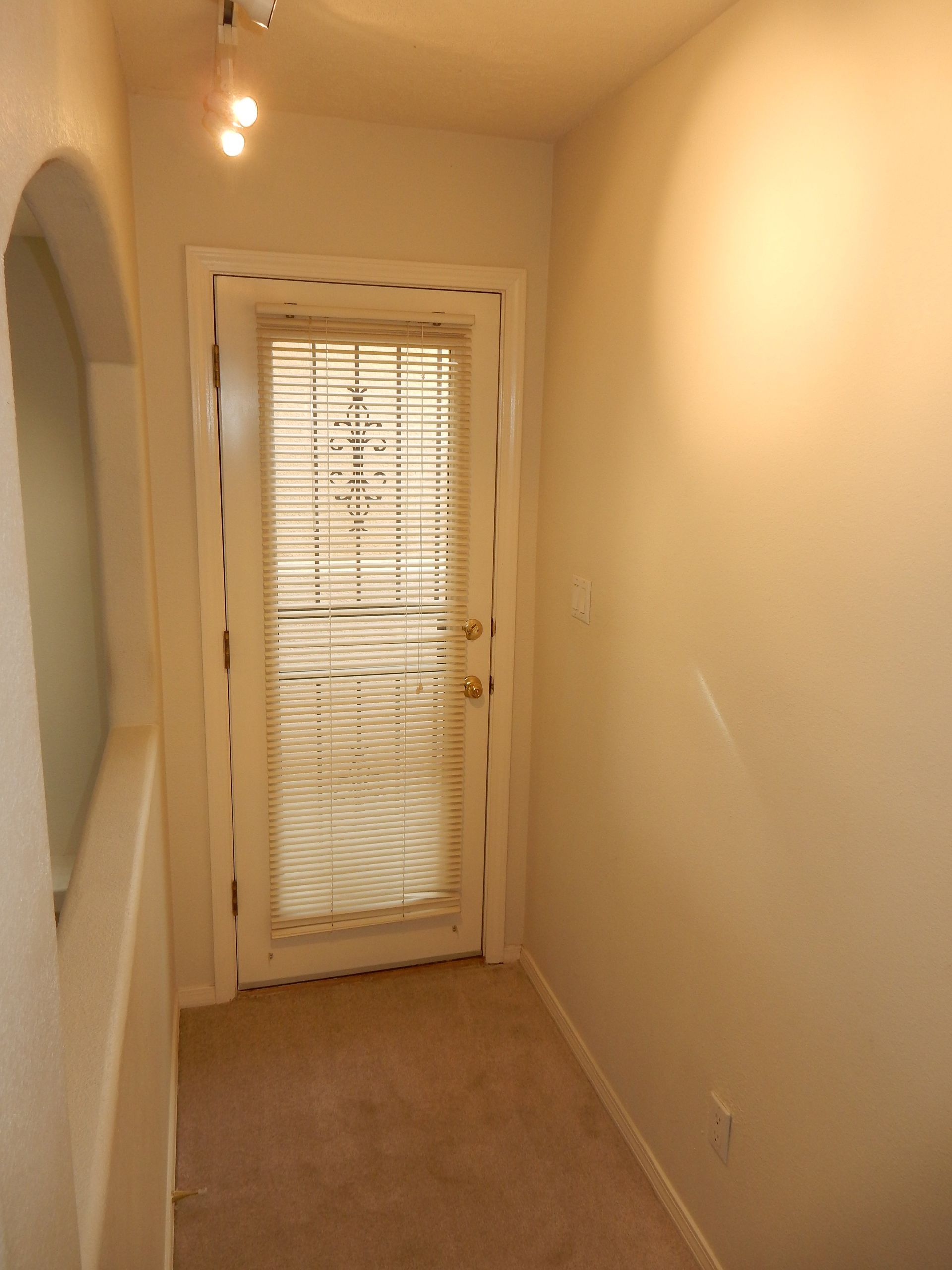 A hallway with a door that has blinds on it