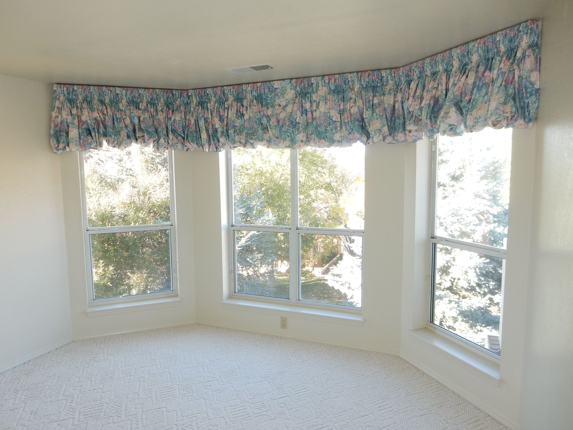 An empty room with a lot of windows and curtains