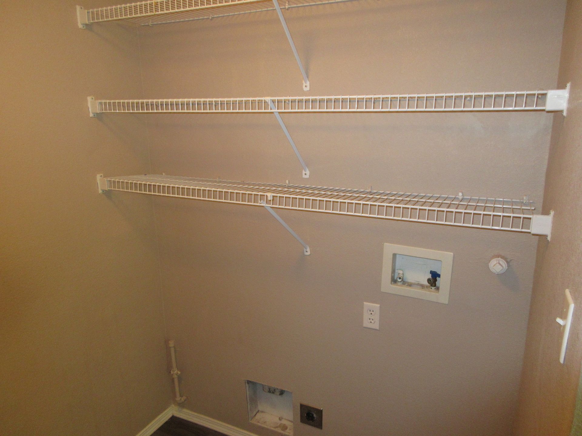 A laundry room with a washer and dryer and shelves.