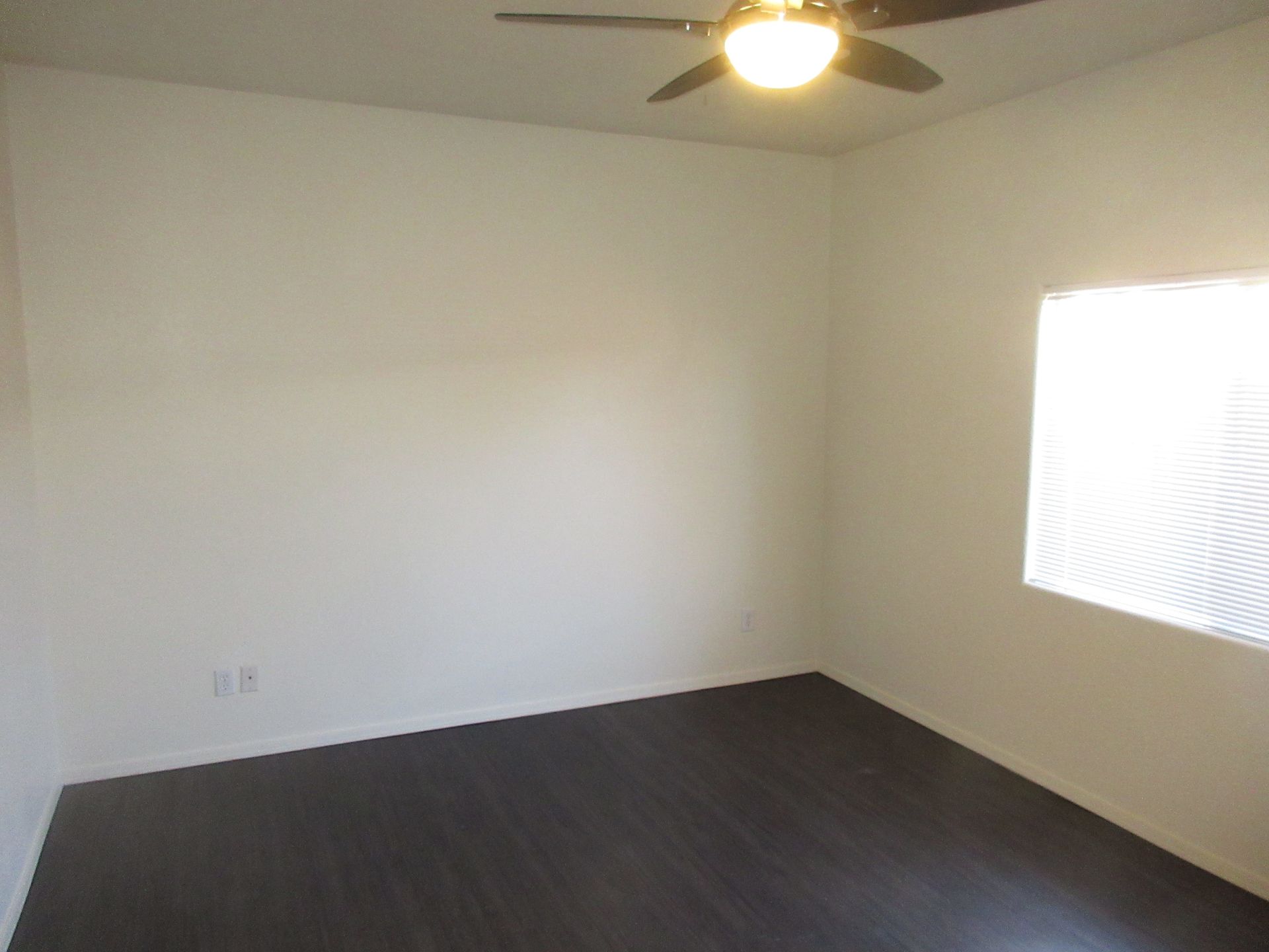 An empty room with a ceiling fan and a window