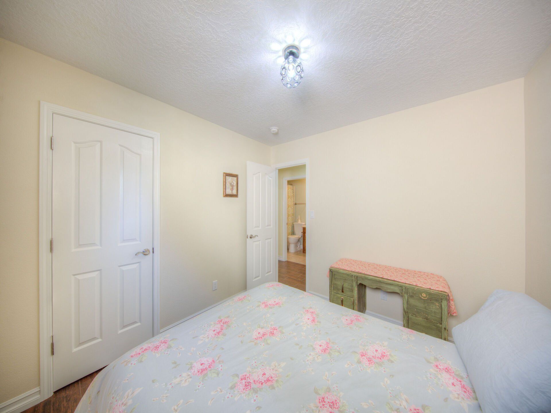 A bedroom with a bed , dresser , and door leading to a bathroom.