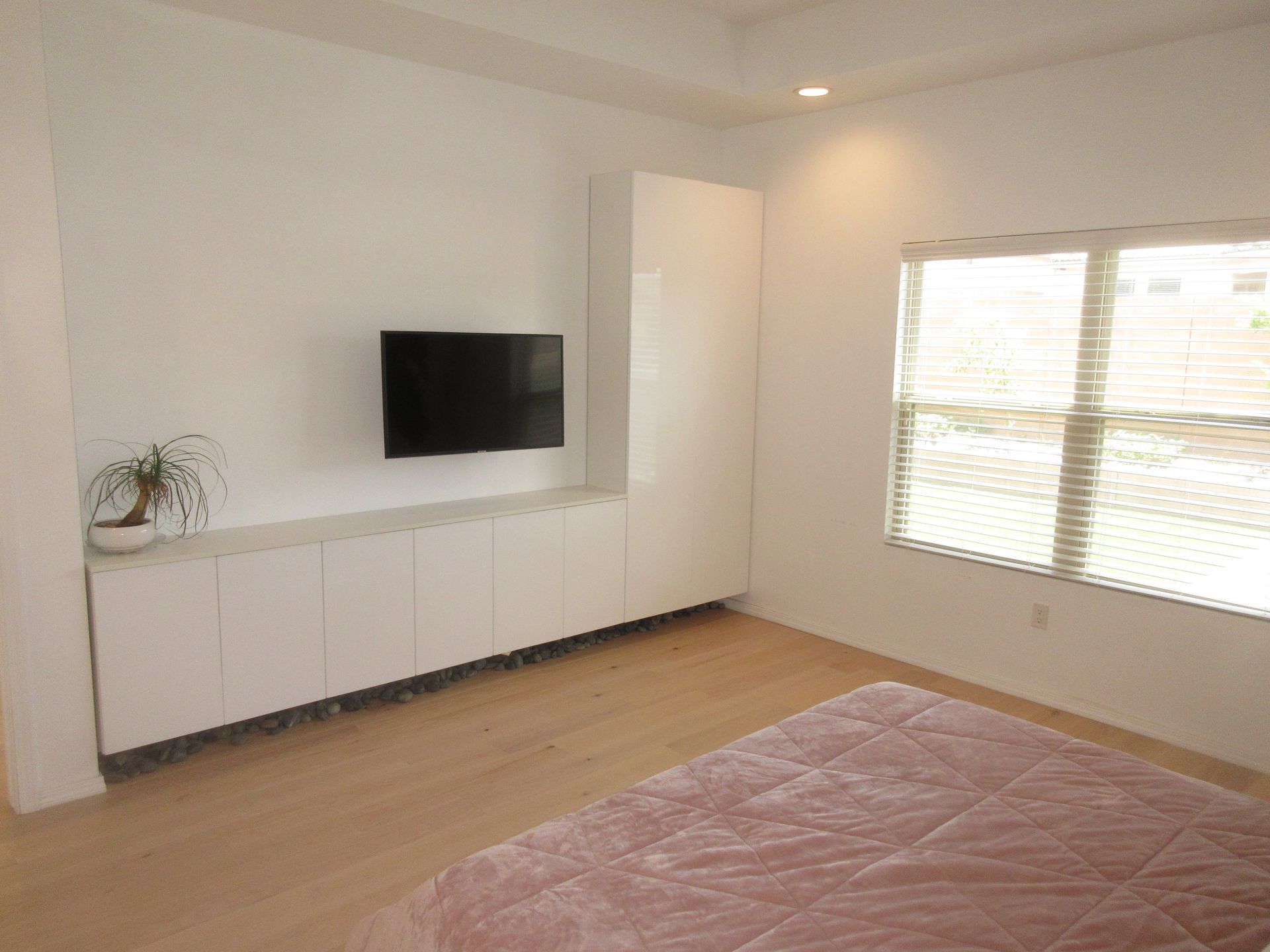 A bedroom with a bed , television , and window.