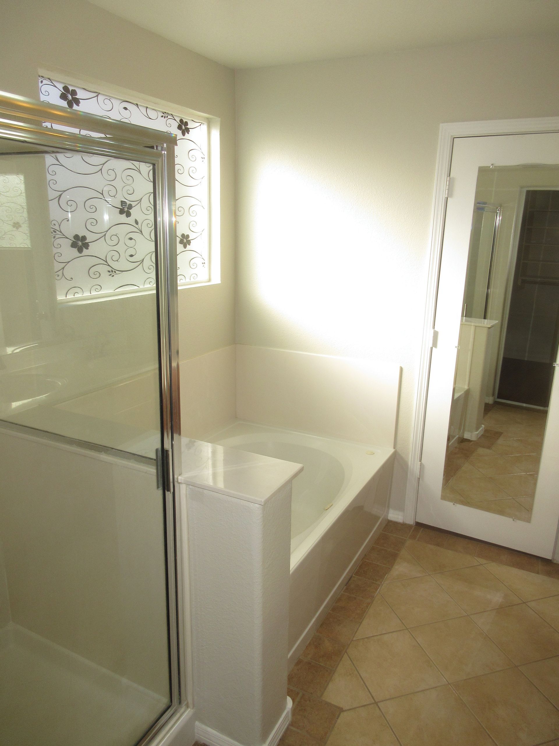 A bathroom with a tub , shower and mirror