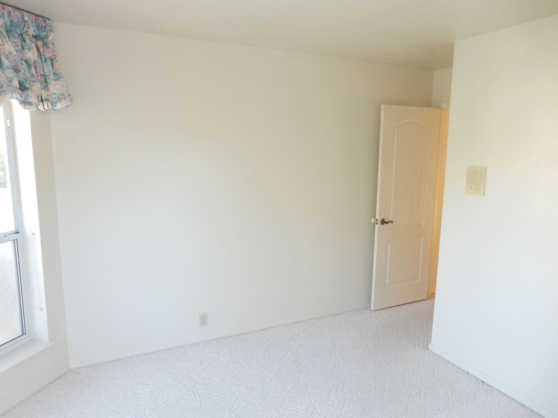 An empty bedroom with white walls and a door