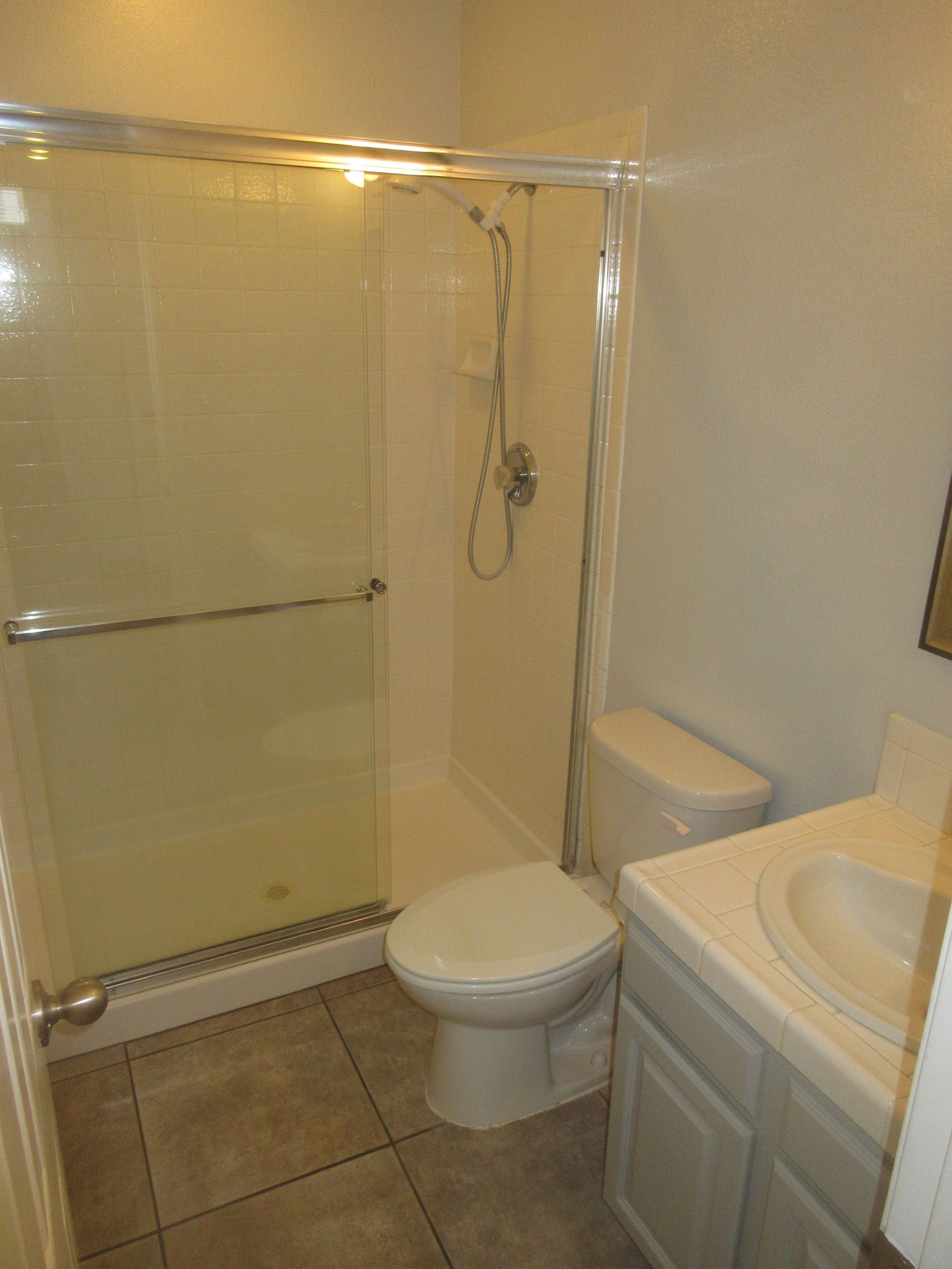 A bathroom with a toilet , sink and shower.