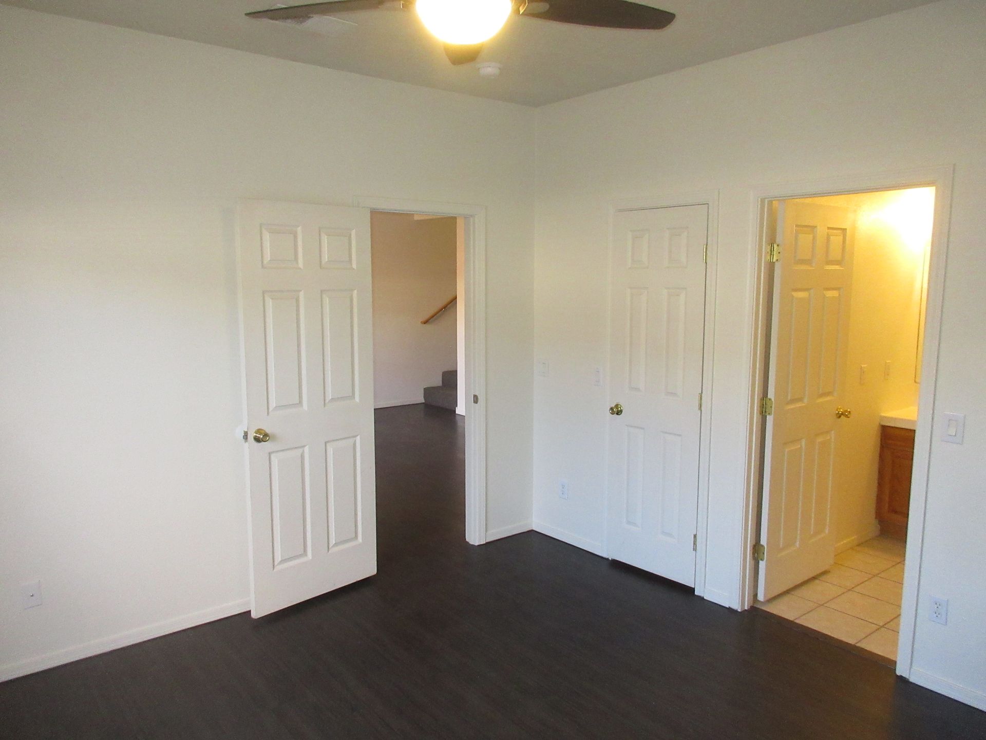 An empty room with a ceiling fan and stairs
