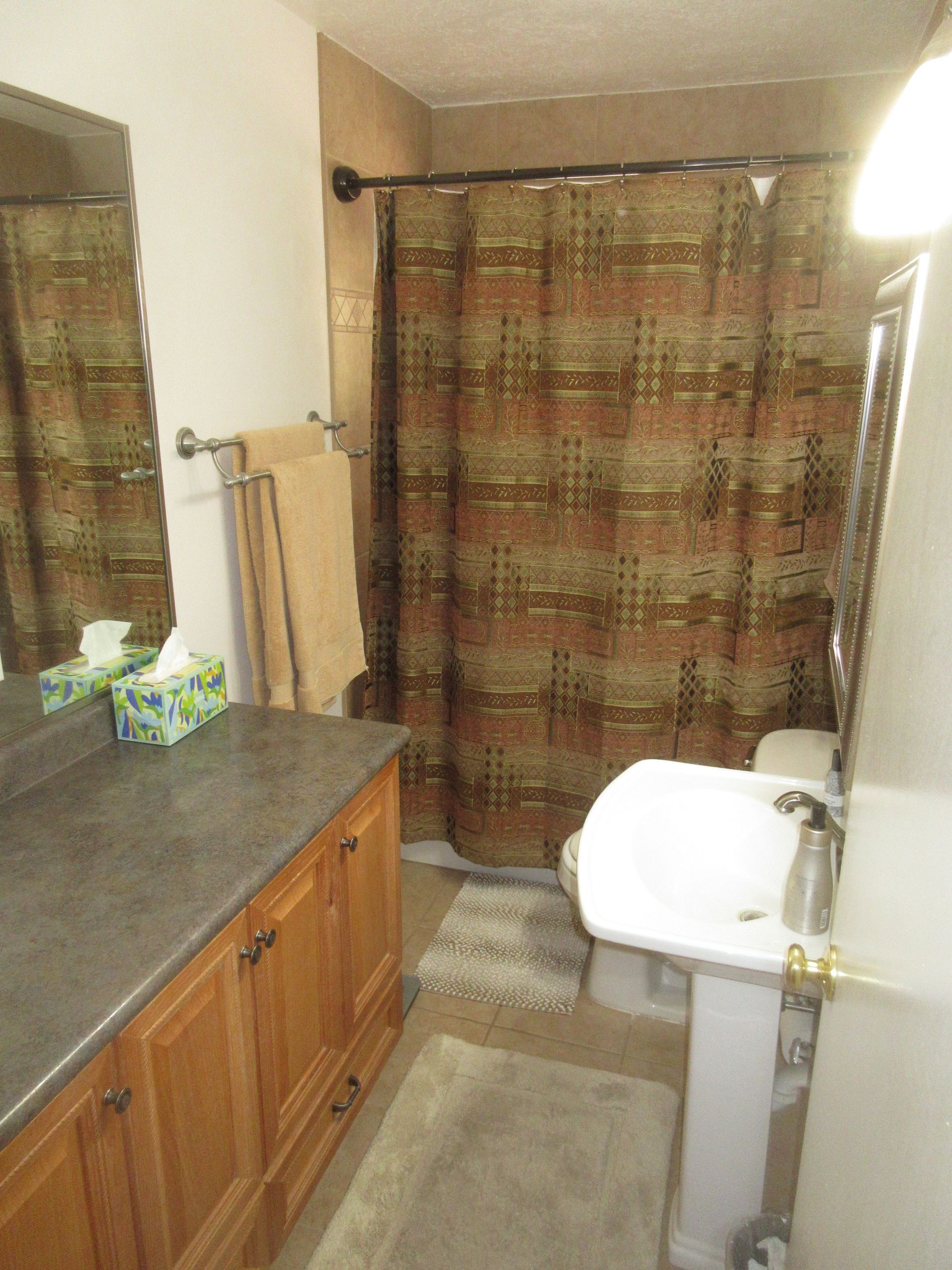 A bathroom with a sink a toilet and a shower curtain