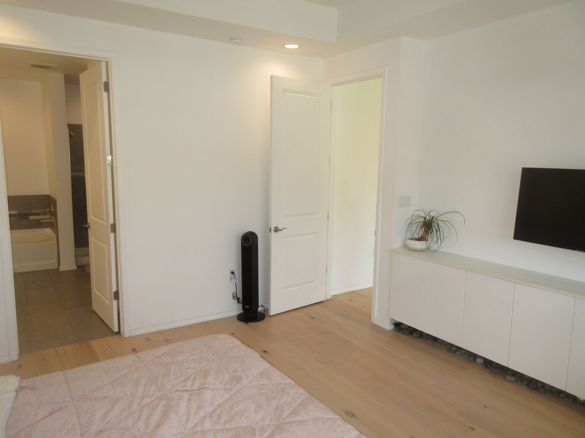 A bedroom with a bed and a television on the wall.