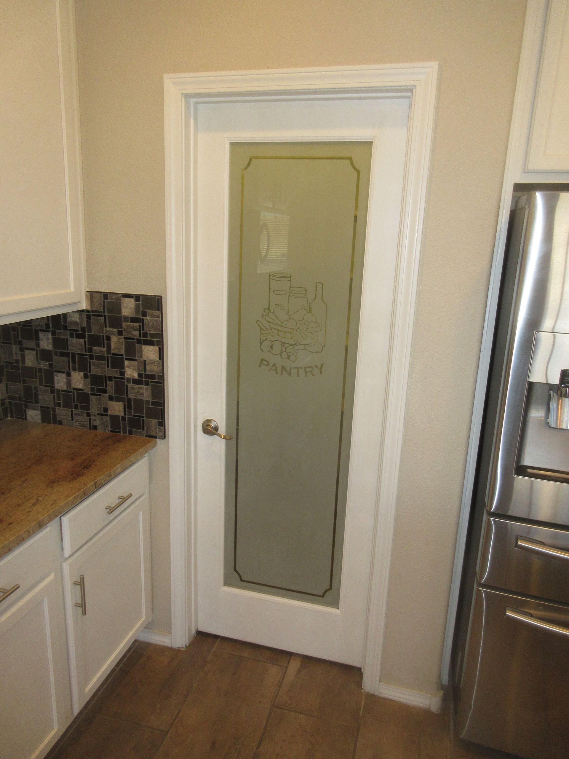 A kitchen with a stainless steel refrigerator and a glass door