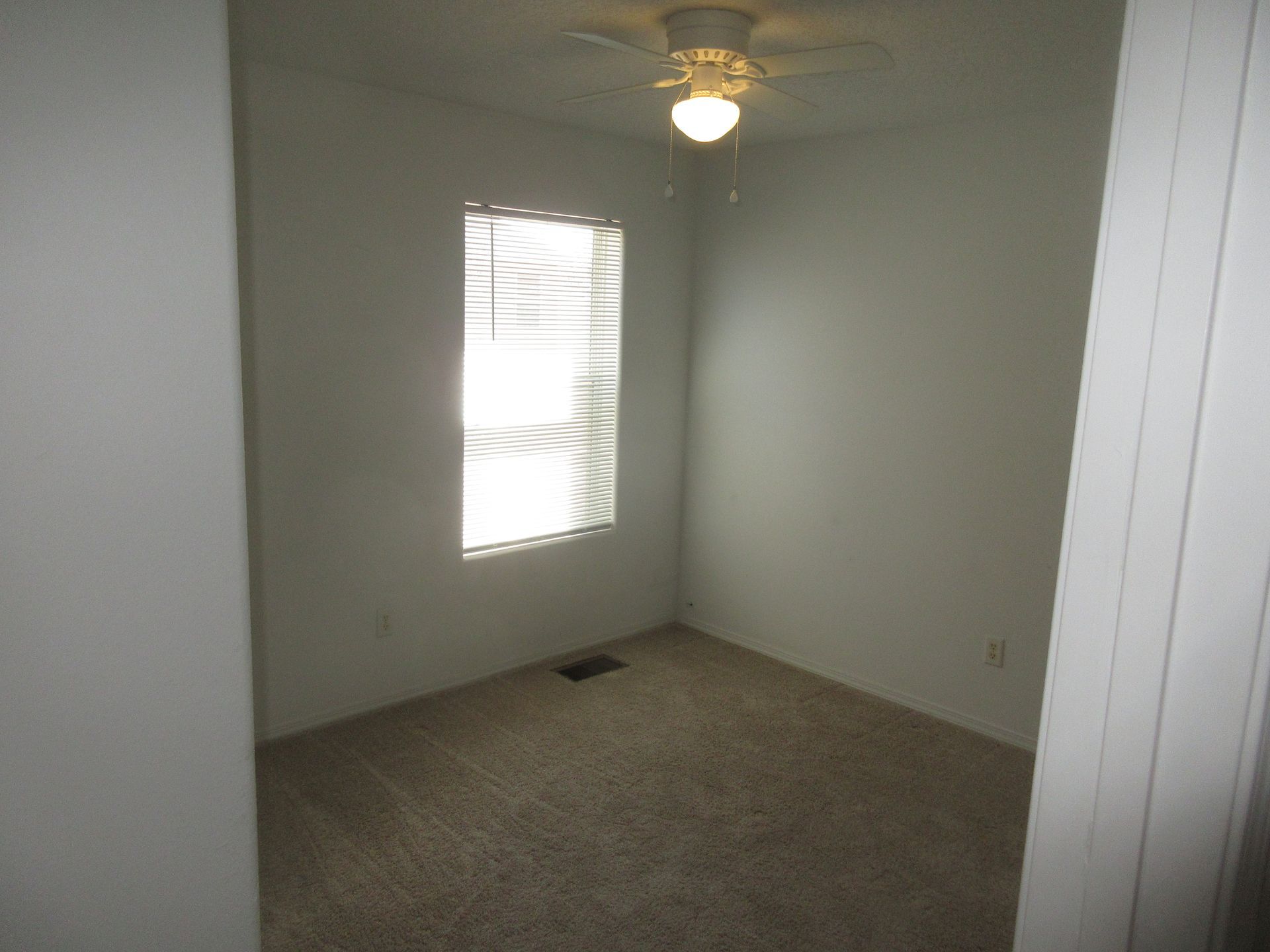 An empty room with a ceiling fan and a window