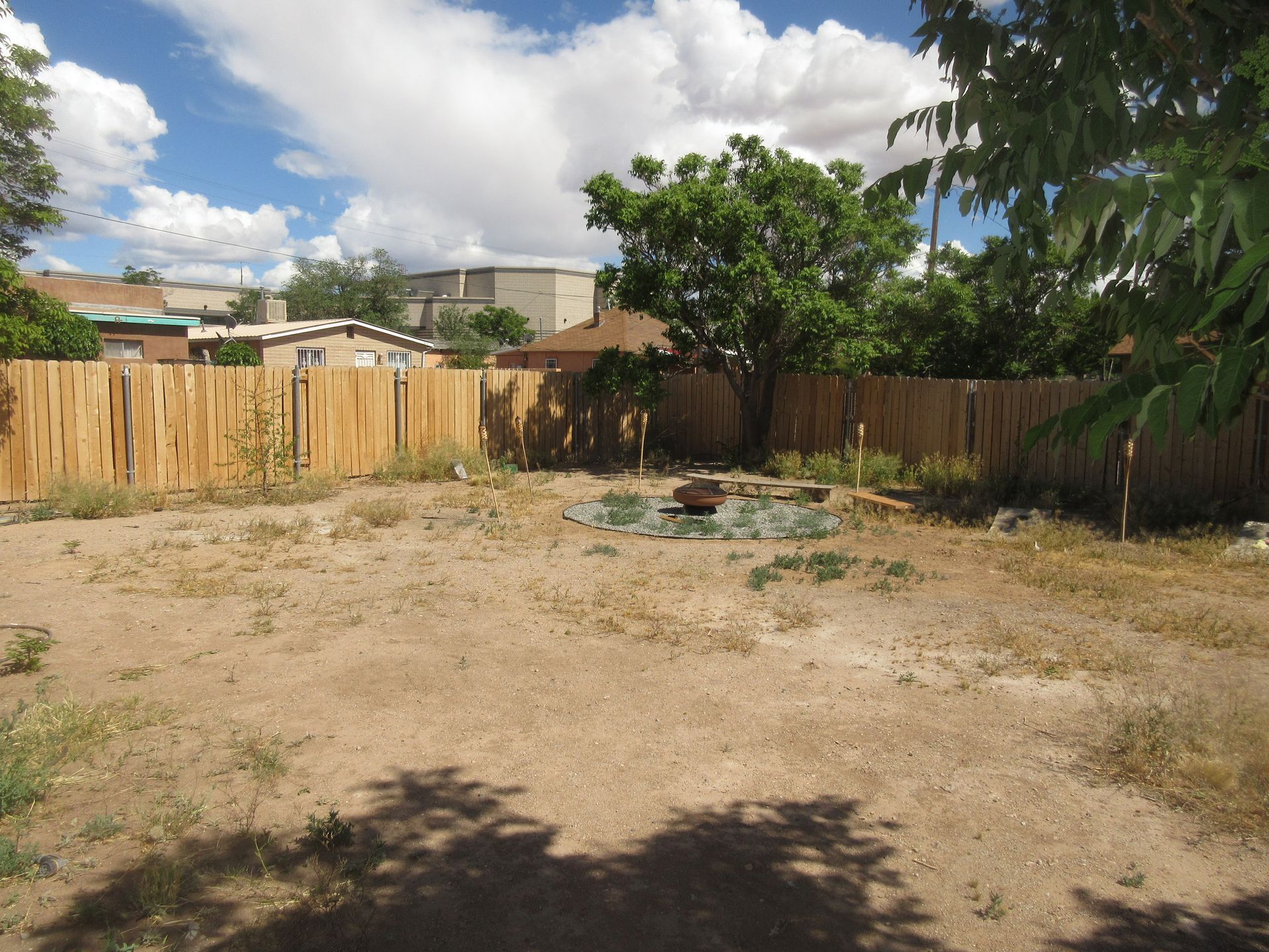 An empty backyard with a wooden fence and trees