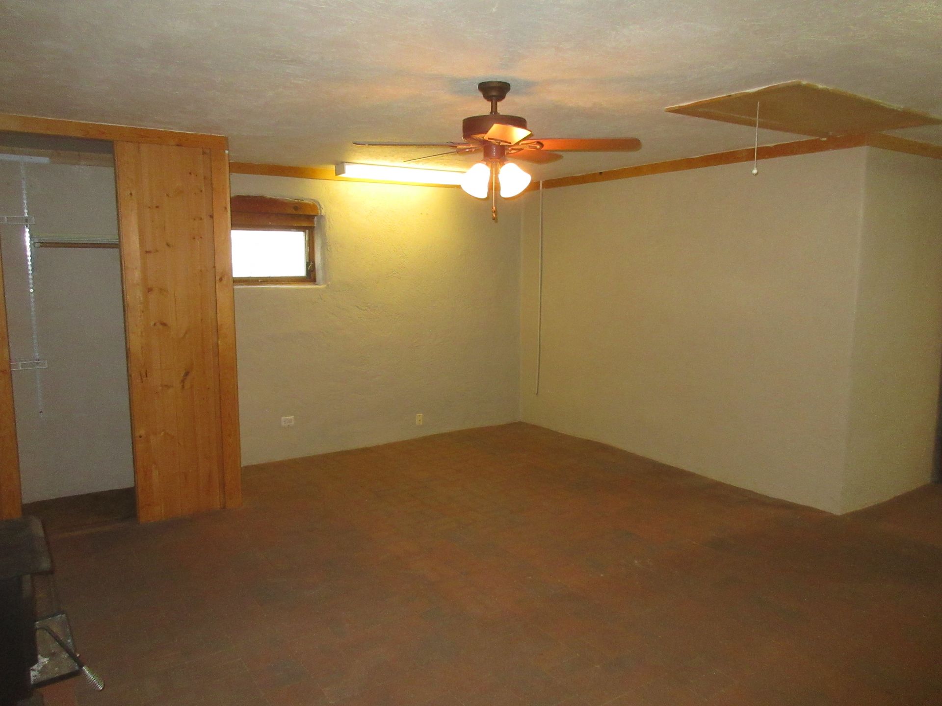 An empty room with a ceiling fan and a window