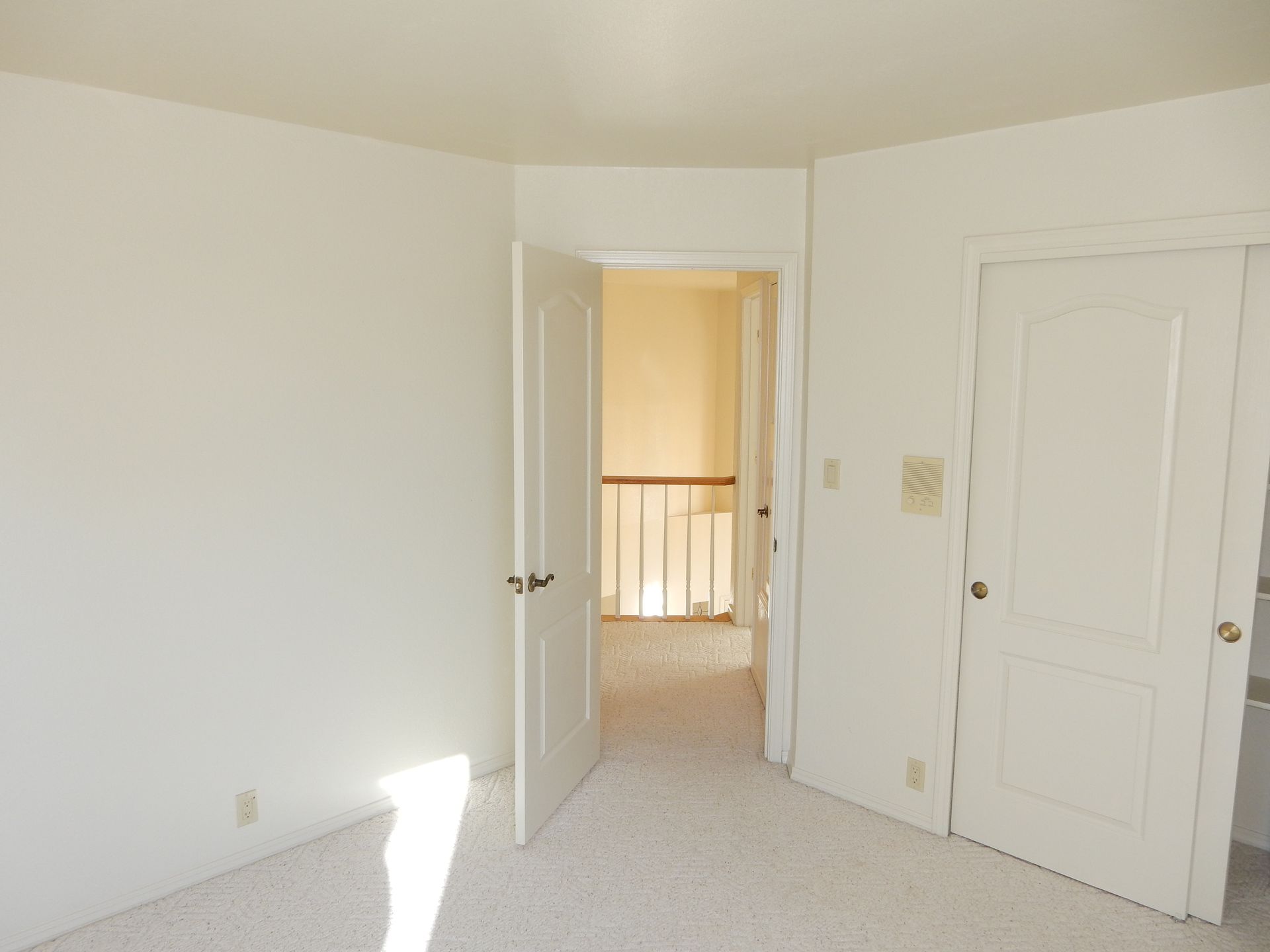 An empty bedroom with white walls and carpet