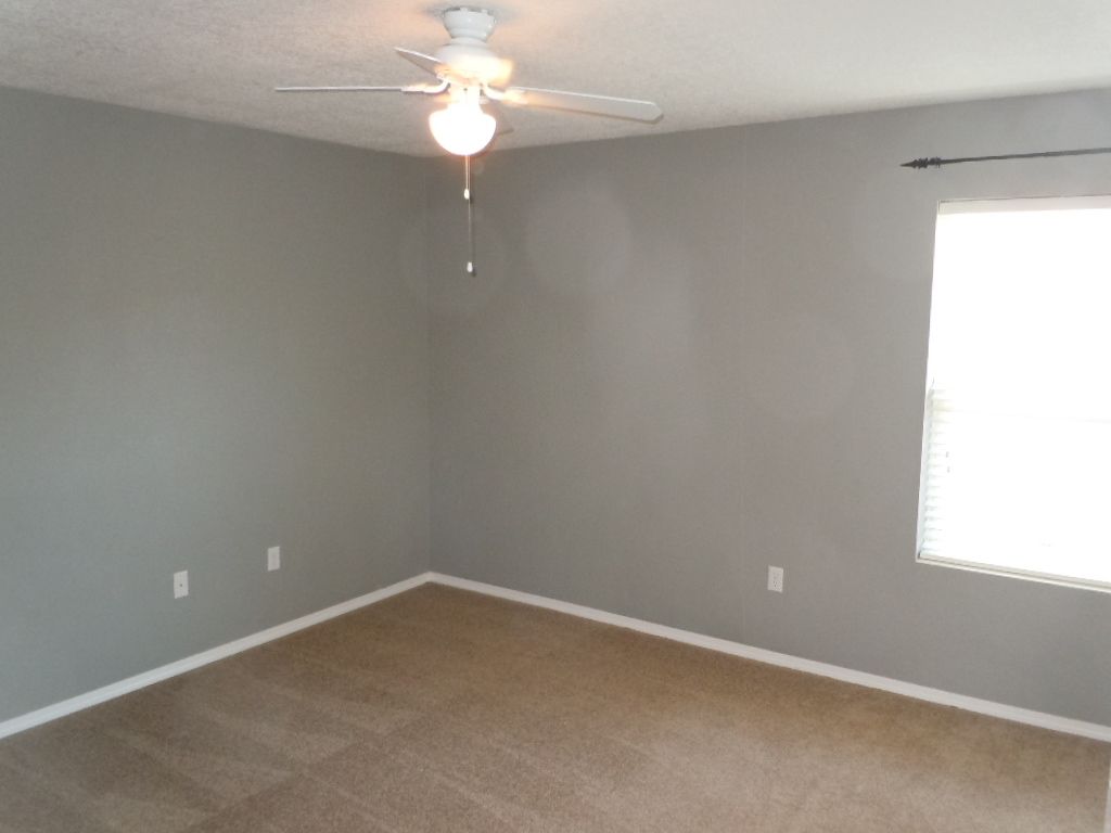 An empty bedroom with a ceiling fan and a window.