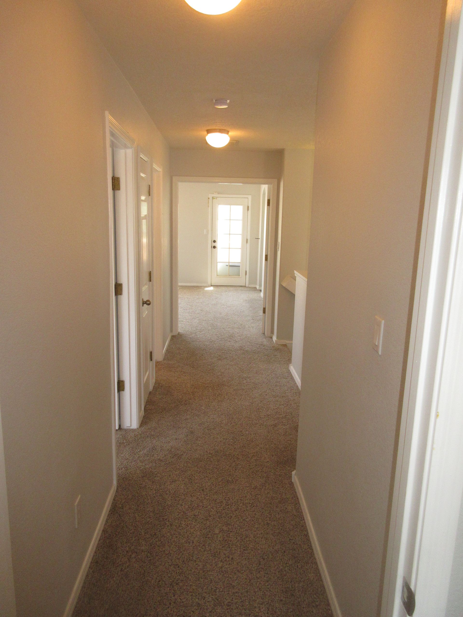 A long hallway in a house with a carpeted floor