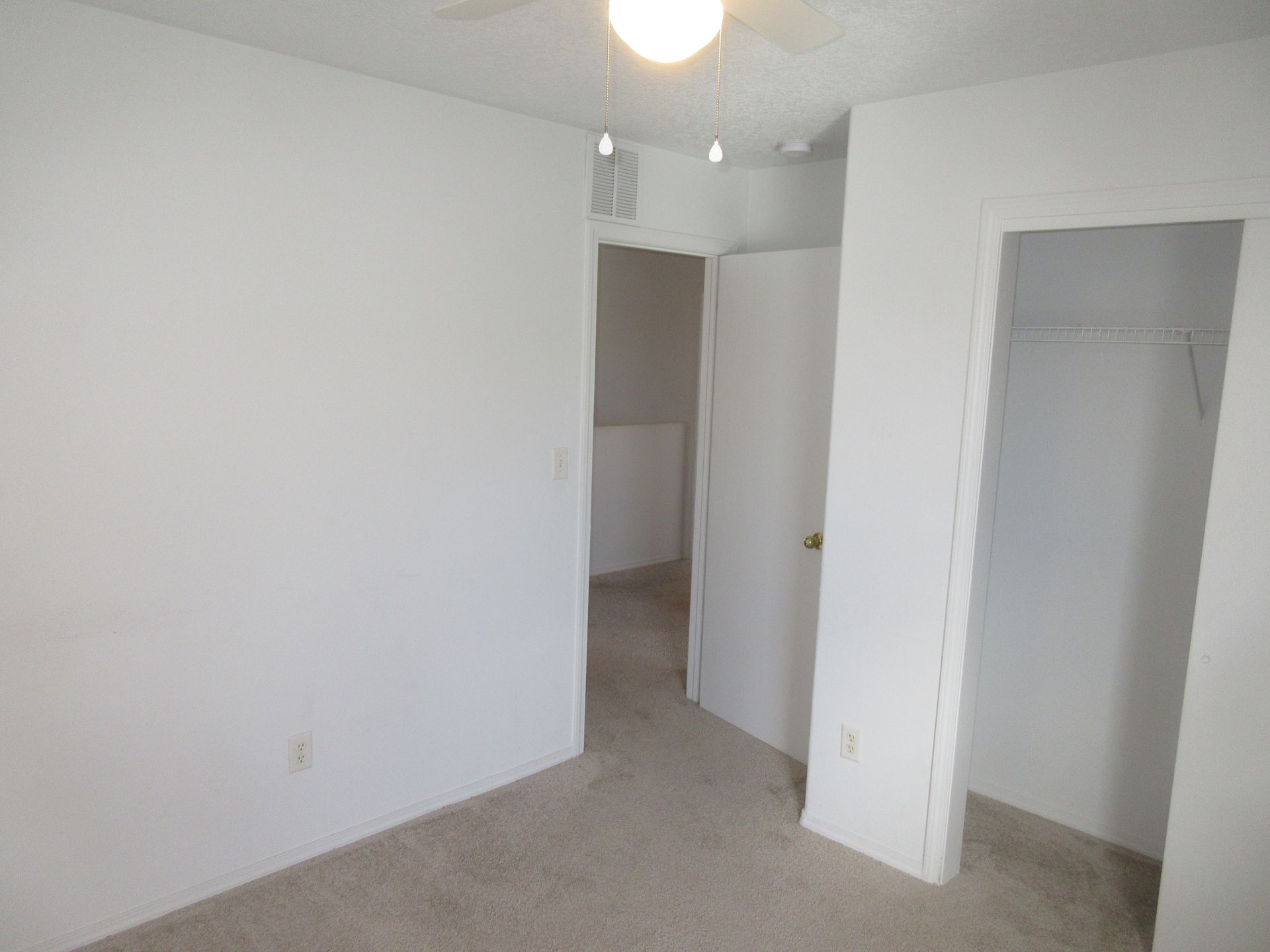 An empty bedroom with a ceiling fan and a closet.