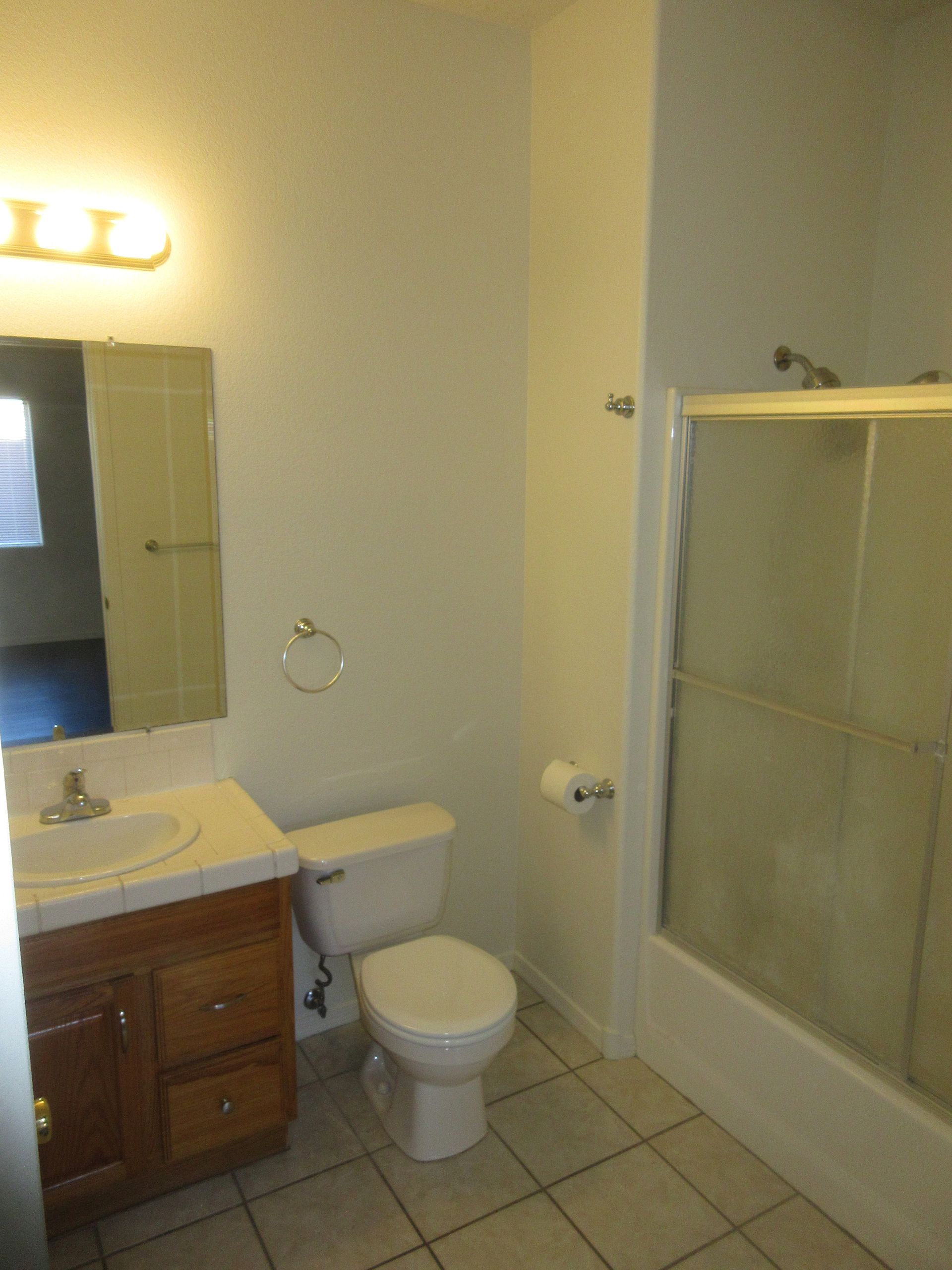 A bathroom with a toilet , sink and shower.