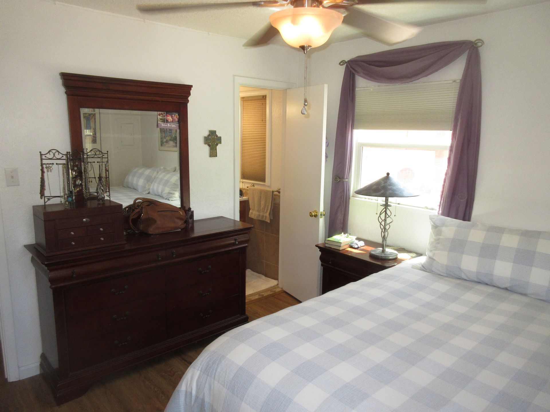 A bedroom with a bed dresser mirror and lamp