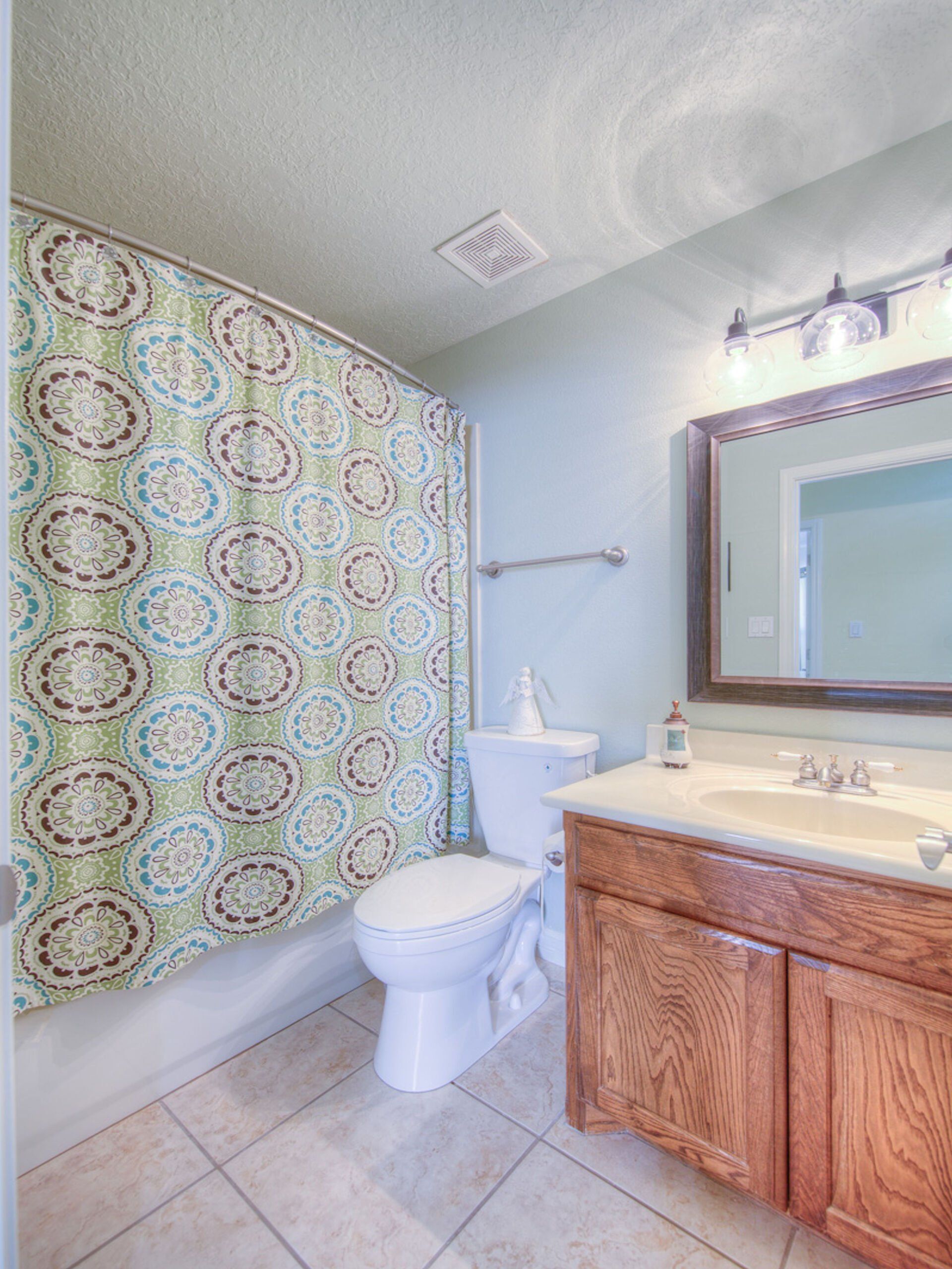 A bathroom with a toilet , sink , and shower curtain.