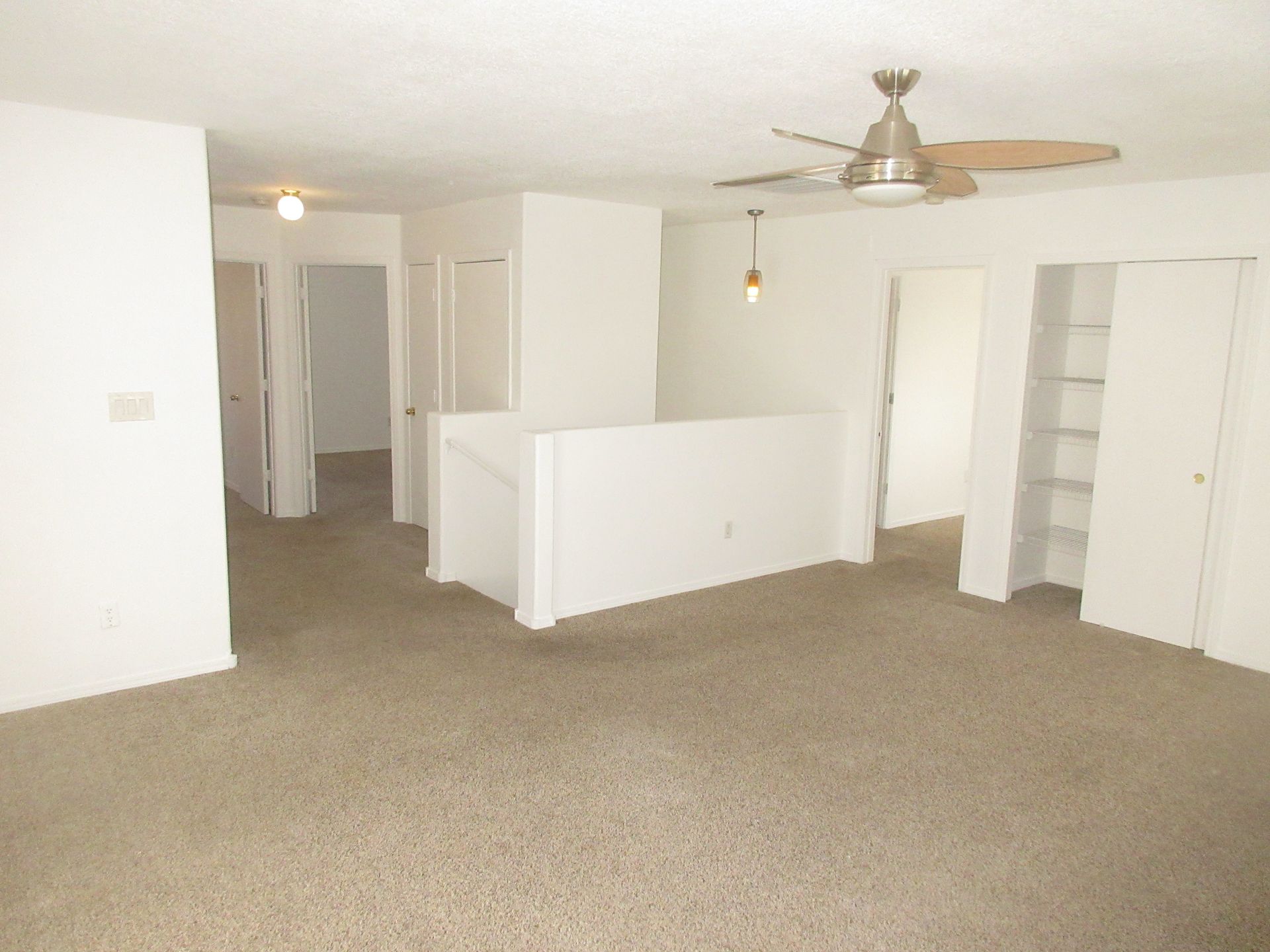 An empty living room with a ceiling fan
