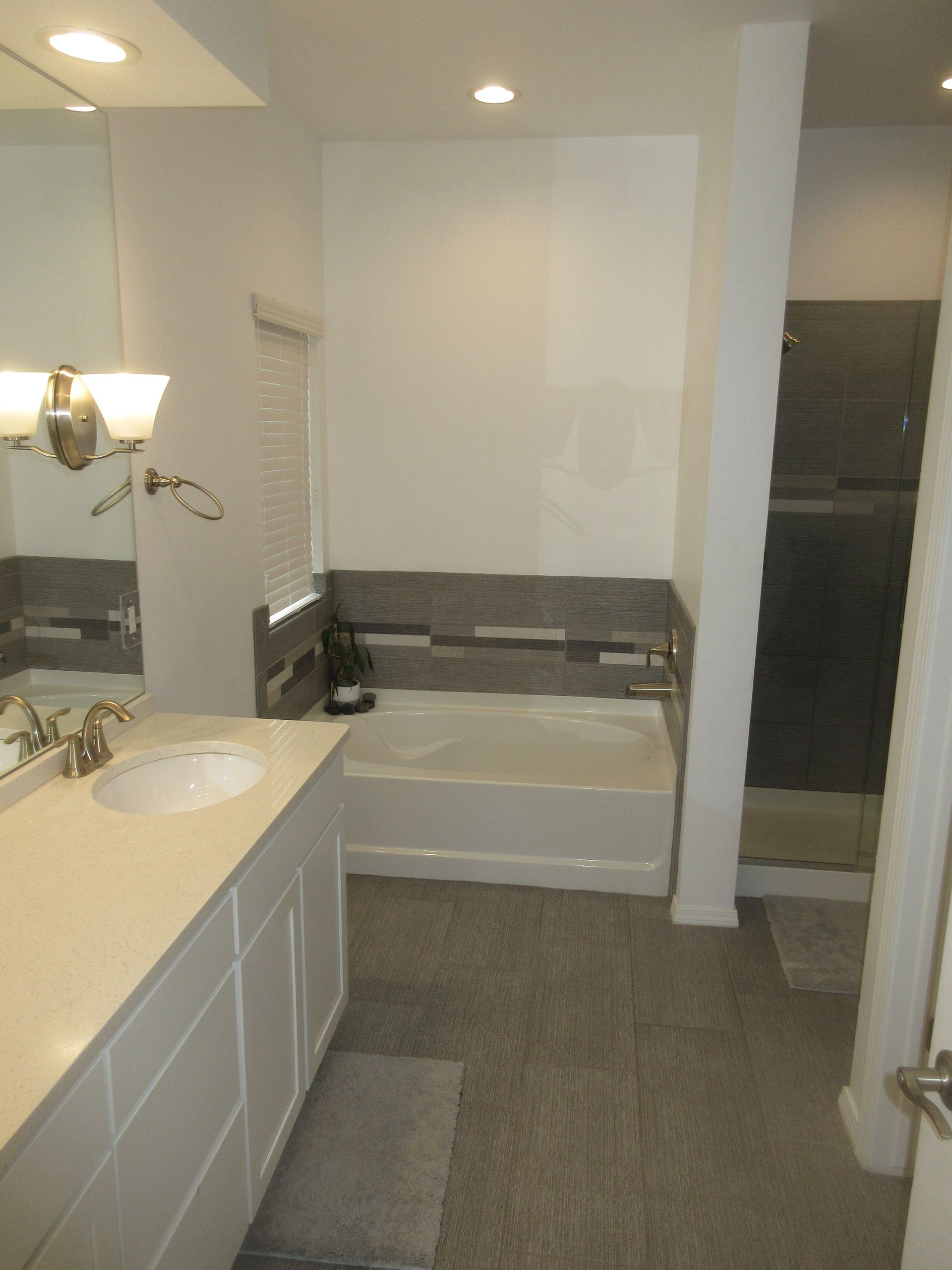 A bathroom with a tub , sink , mirror and shower.