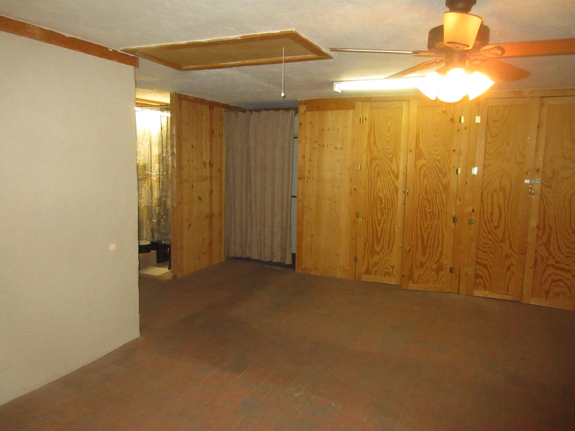 An empty room with wooden walls and a ceiling fan