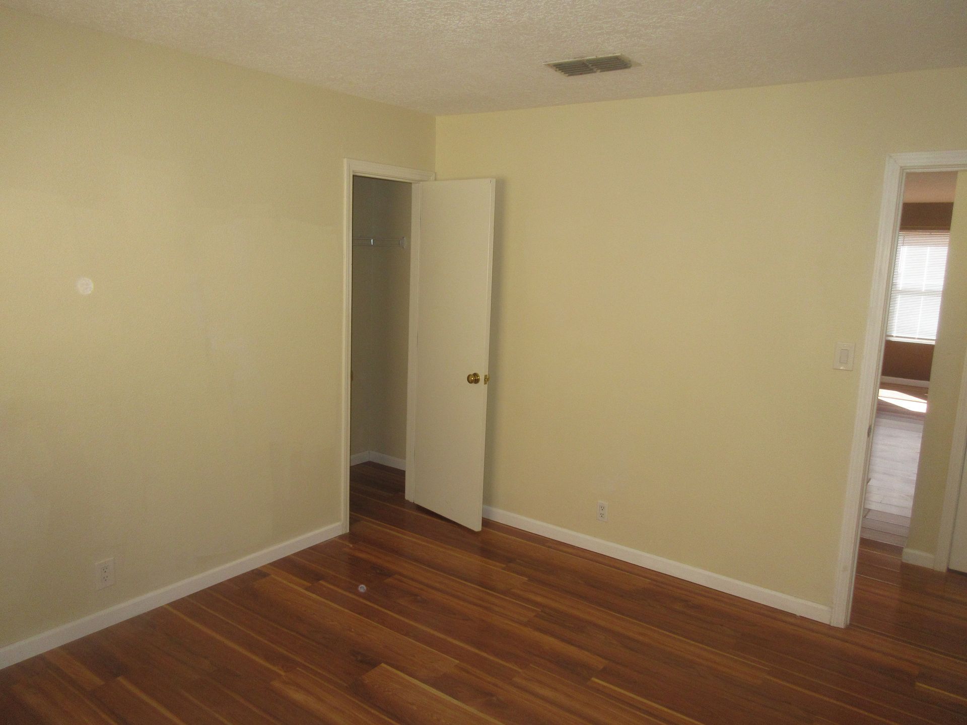An empty bedroom with hardwood floors and a door that is open.