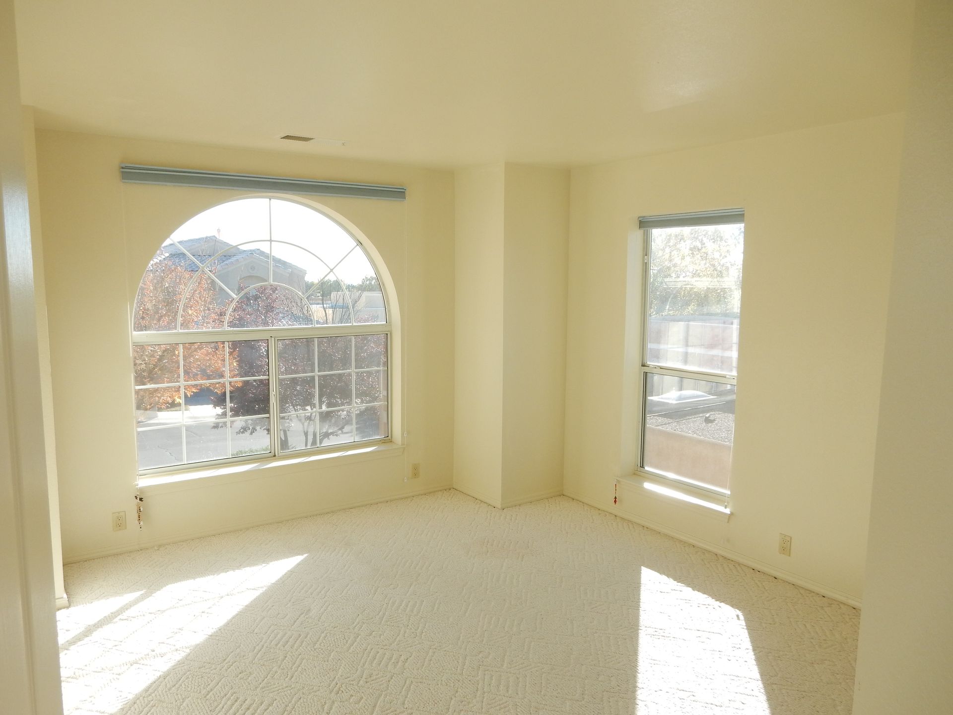 An empty room with two windows and a balcony