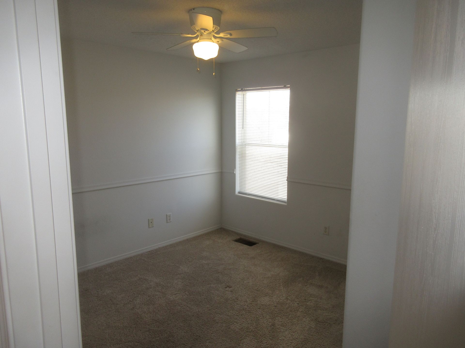 An empty bedroom with a ceiling fan and a window