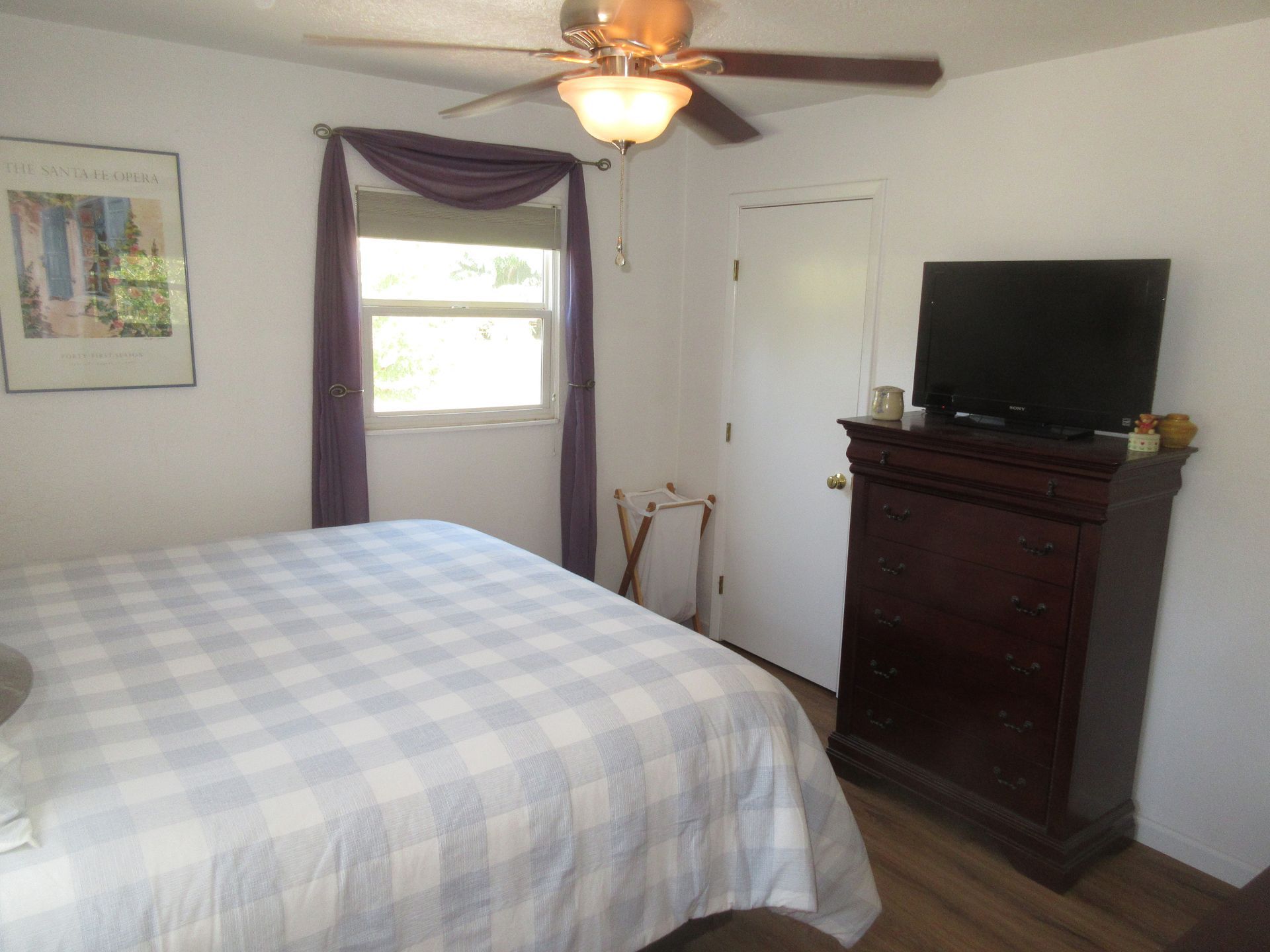 A bedroom with a ceiling fan and a television