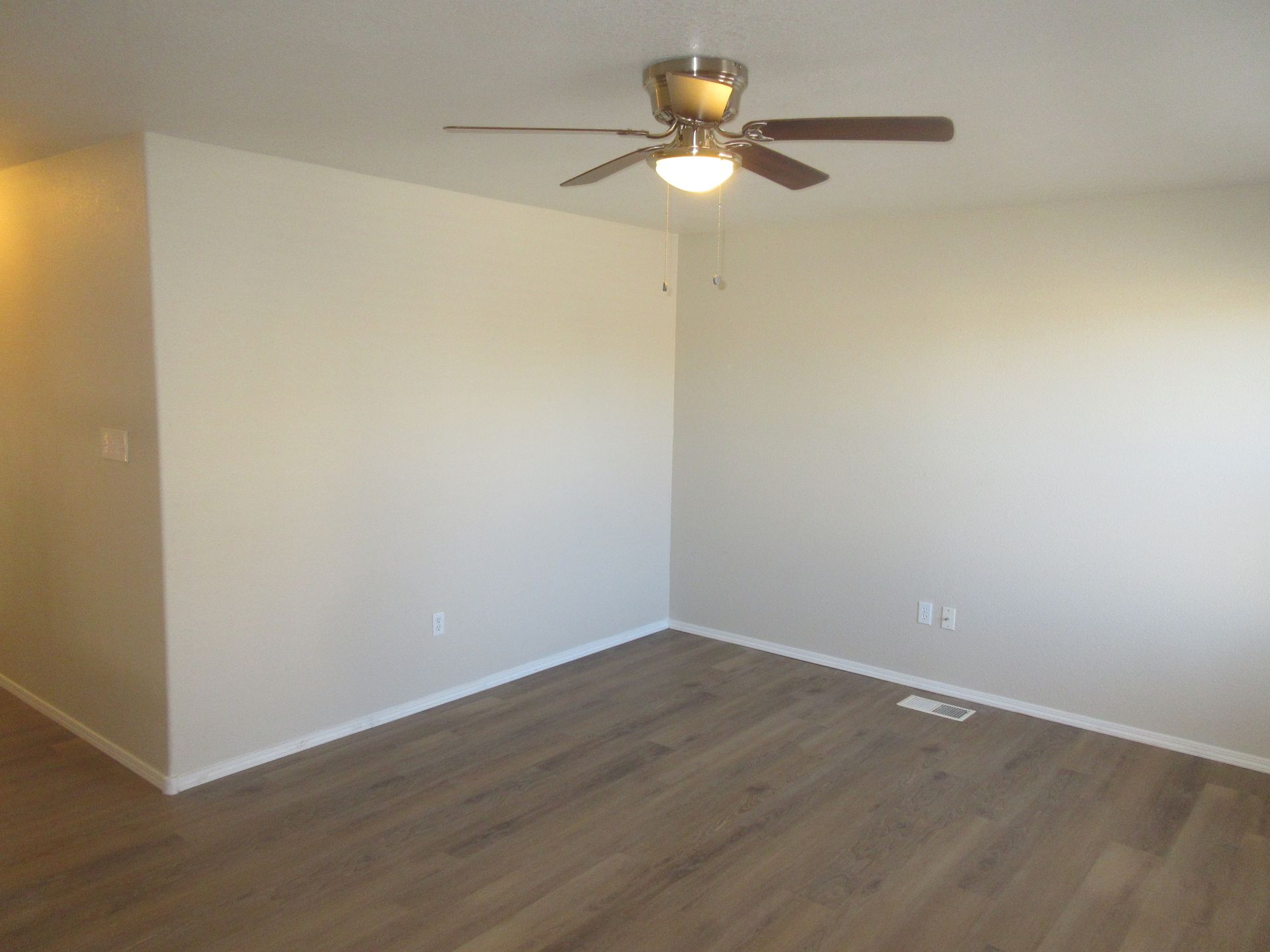 An empty room with a ceiling fan and a light on the ceiling.