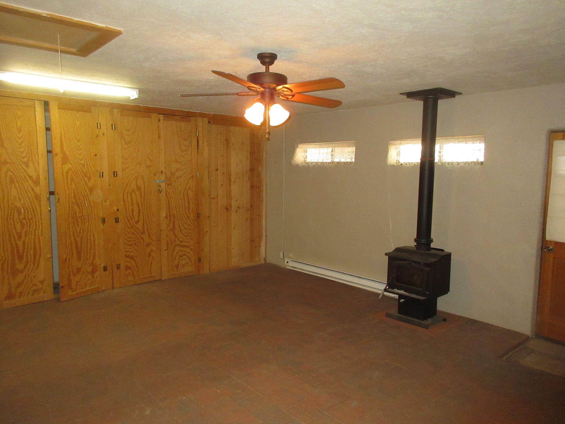 An empty room with a ceiling fan and a wood stove.