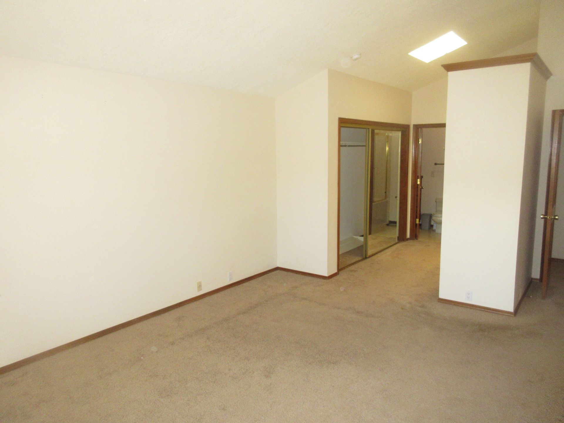 An empty room with a carpeted floor and white walls