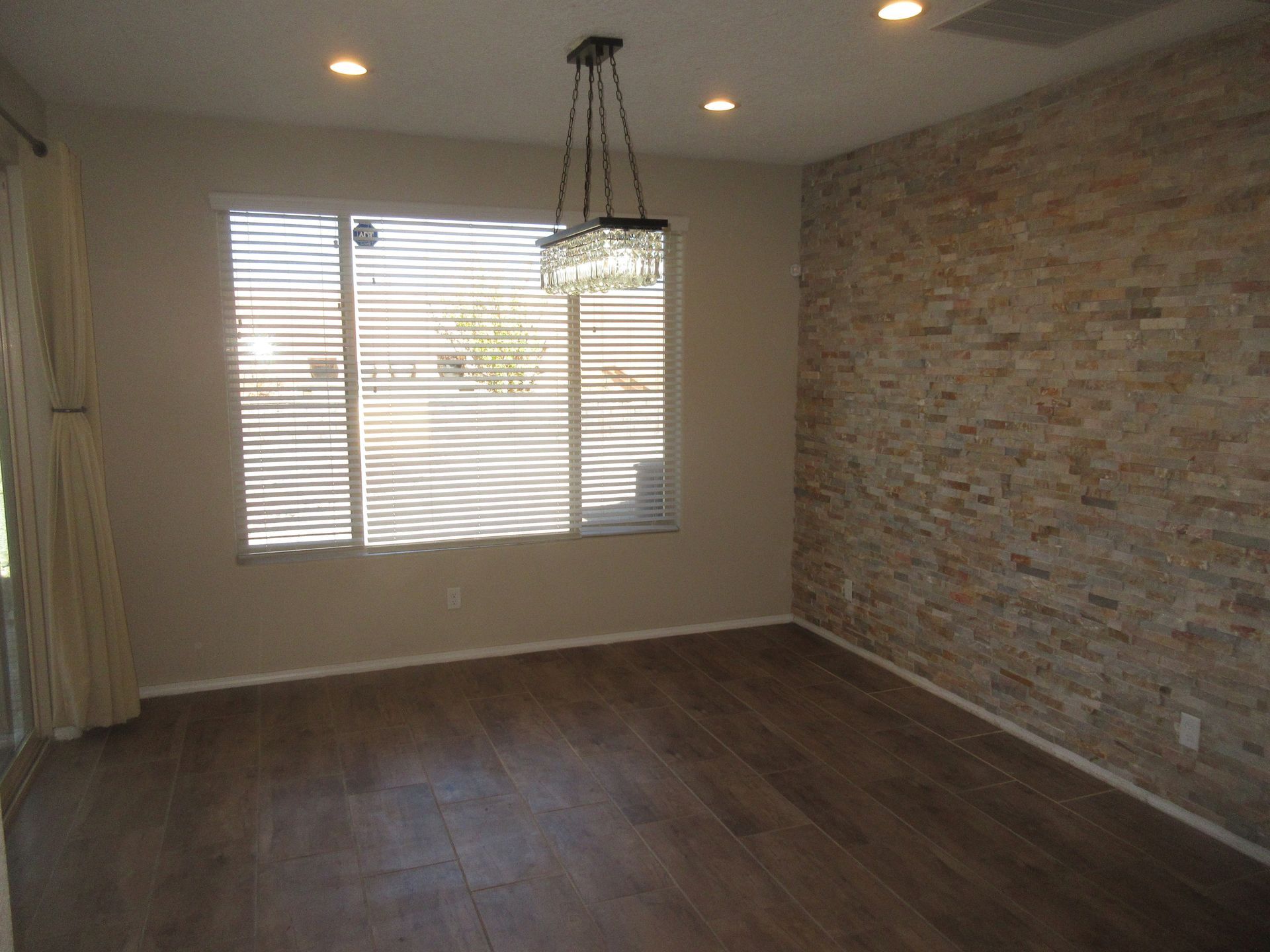 An empty dining room with a brick wall and a large window.