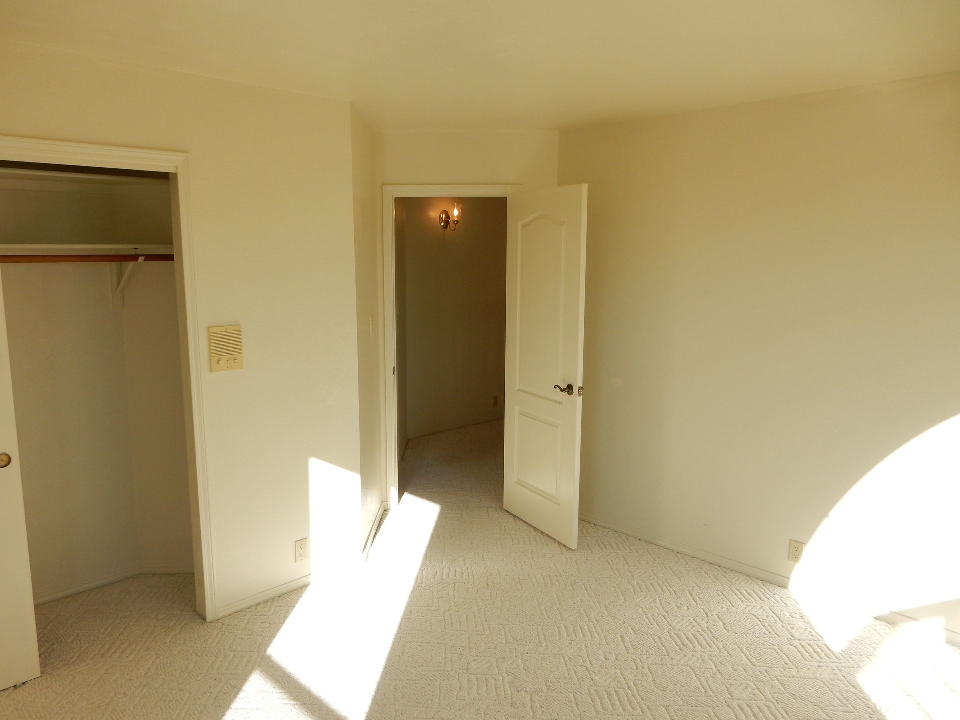 An empty bedroom with a closet and a door open.