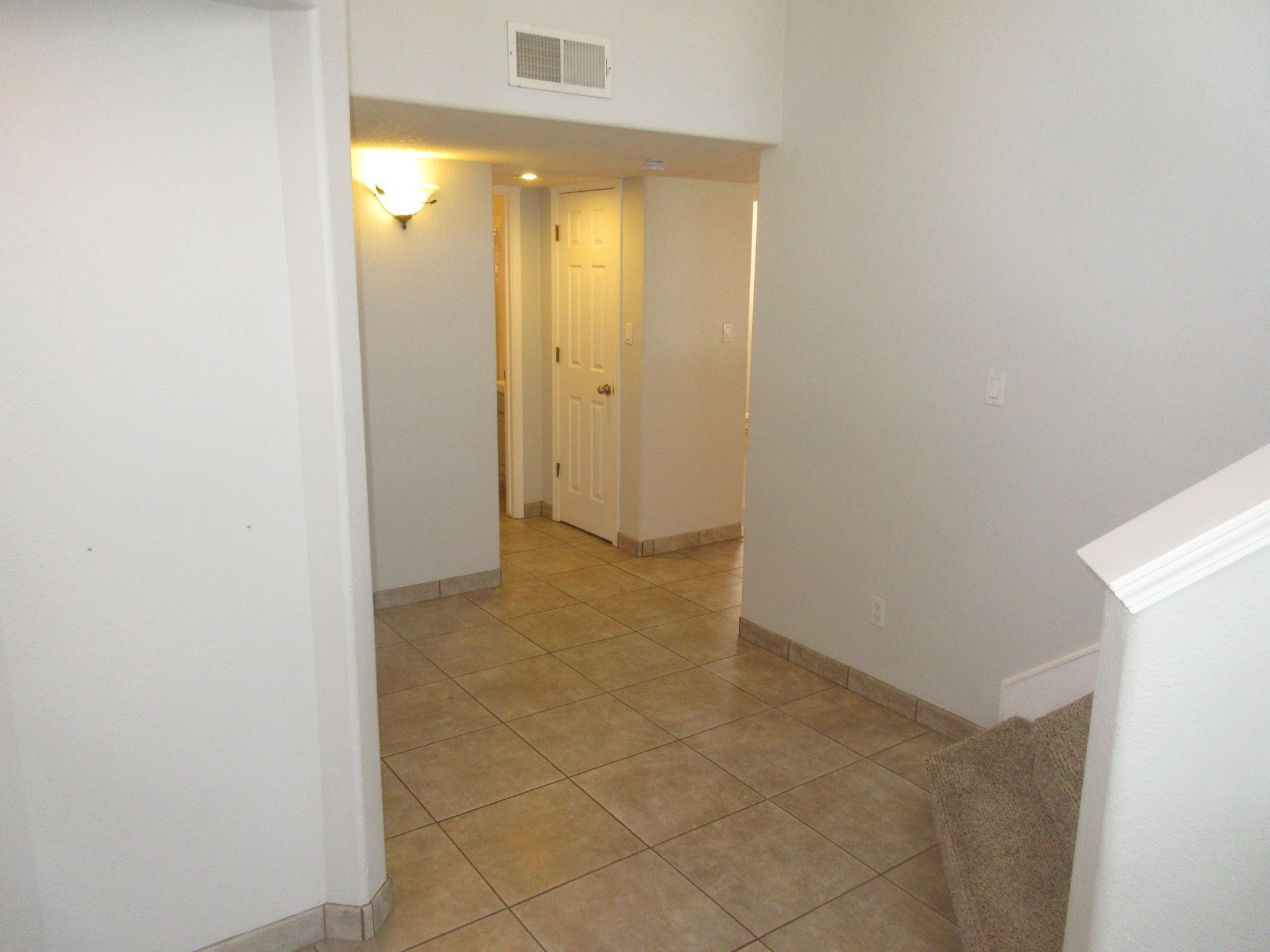 An empty hallway with stairs leading up to the second floor of a house.