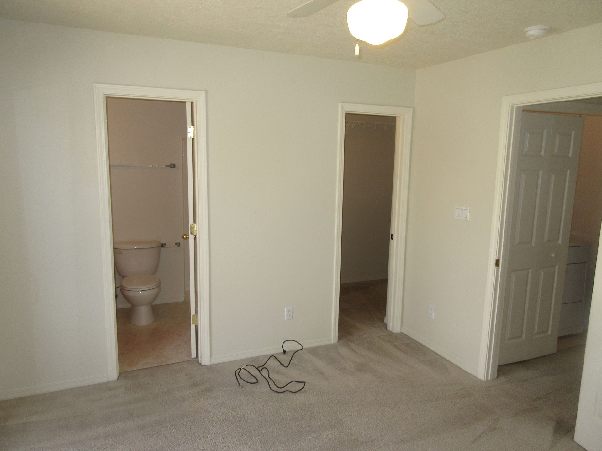 An empty bedroom with a toilet and a ceiling fan