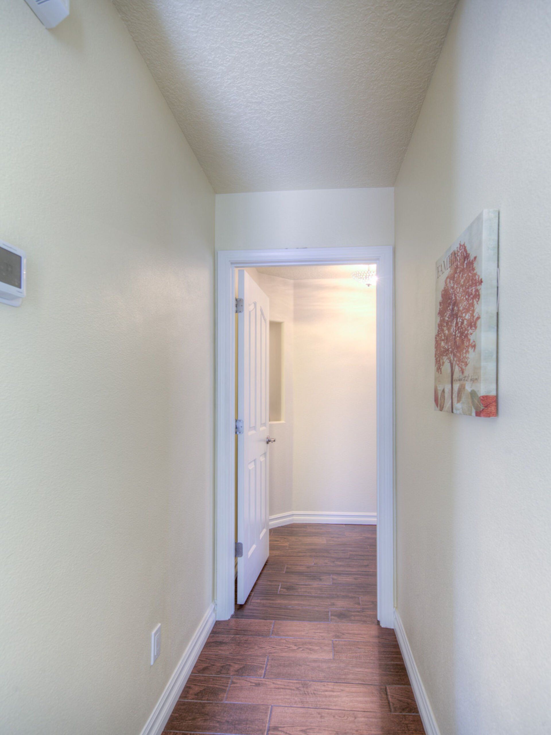 A hallway with hardwood floors and a painting on the wall.
