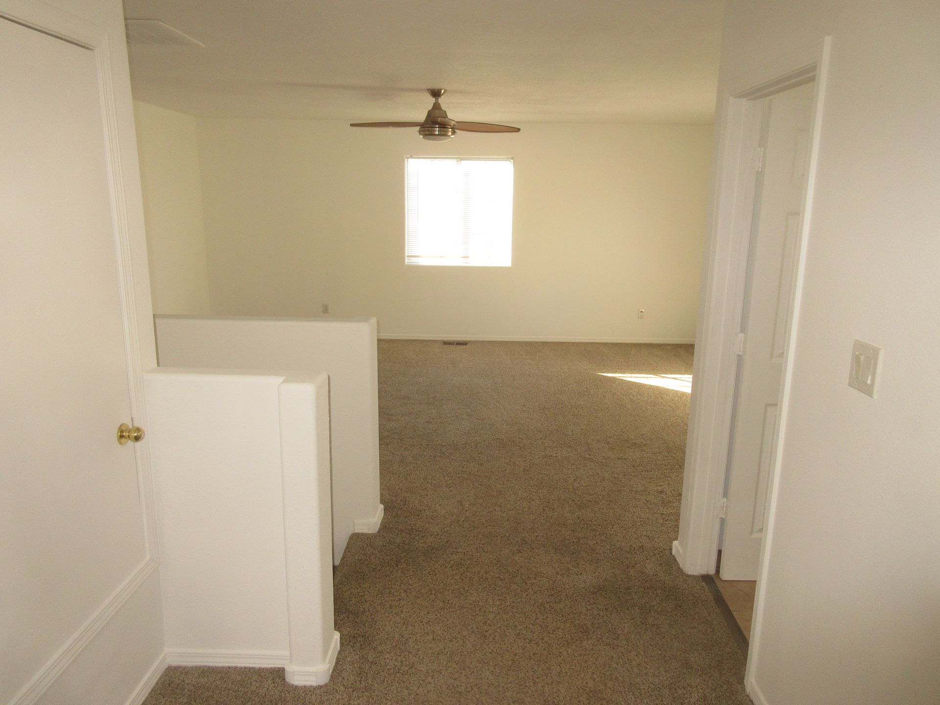 An empty room with a ceiling fan and a window.