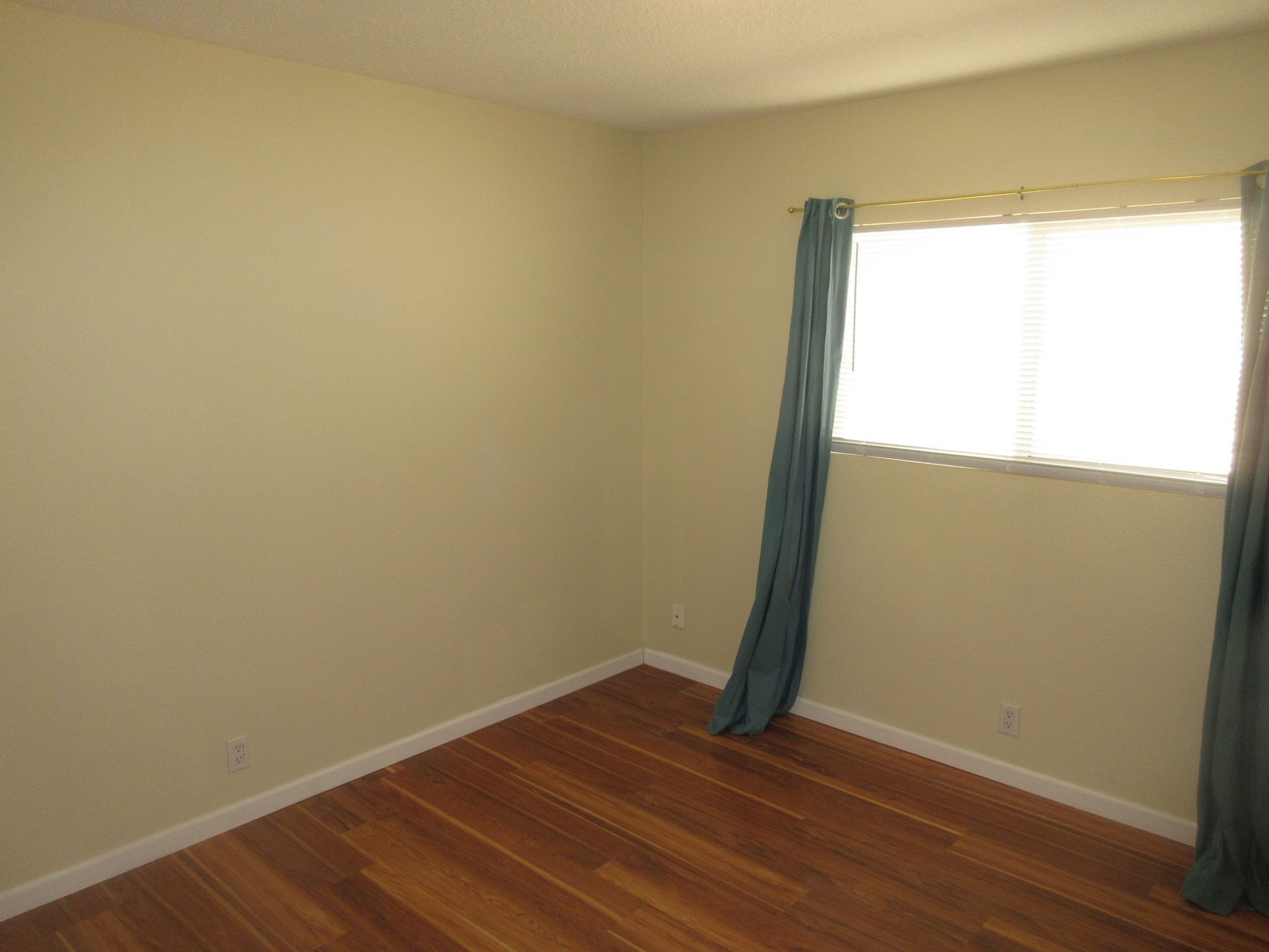 An empty room with hardwood floors and two windows.