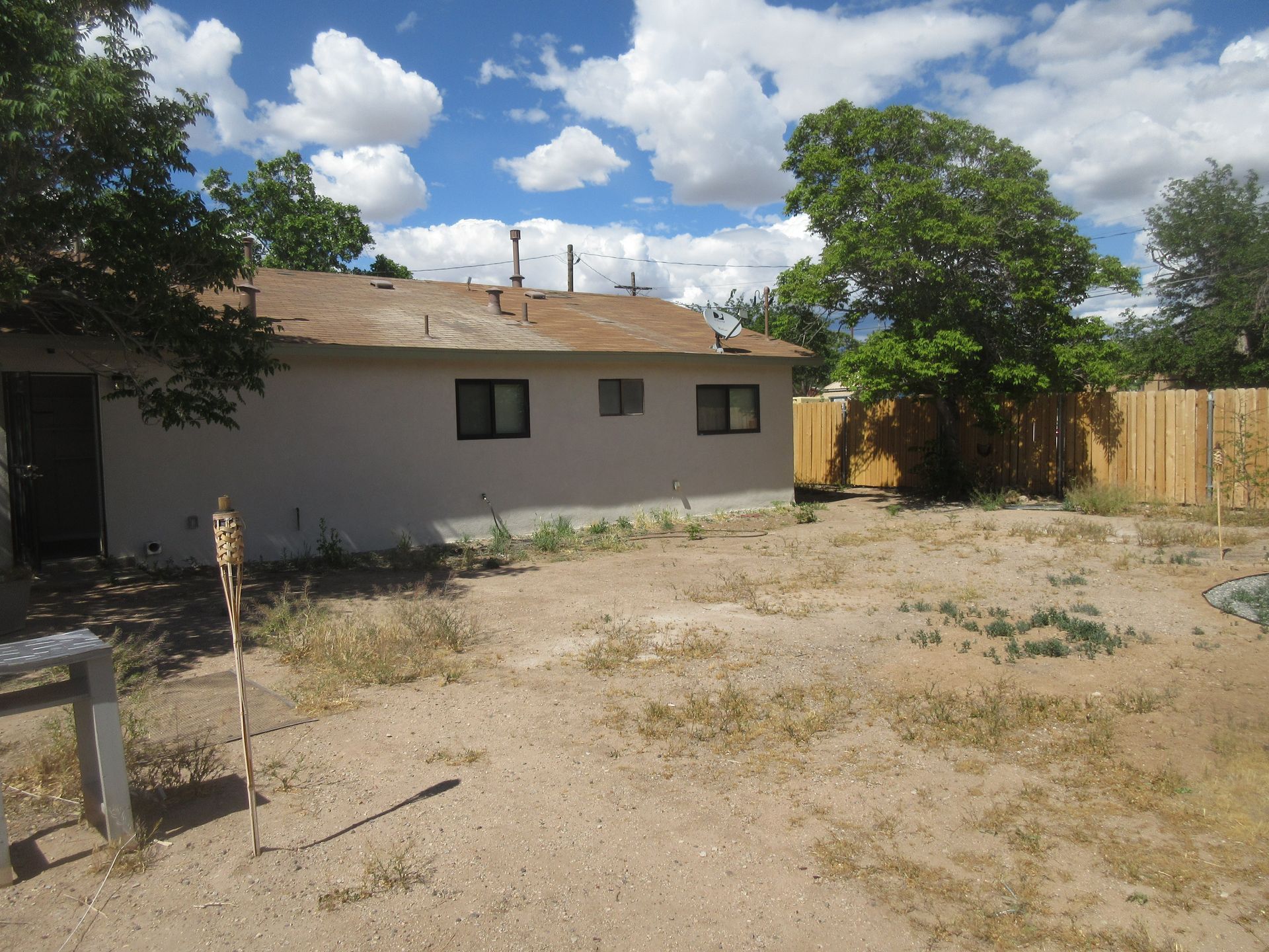 The backyard of a house with a wooden fence and trees