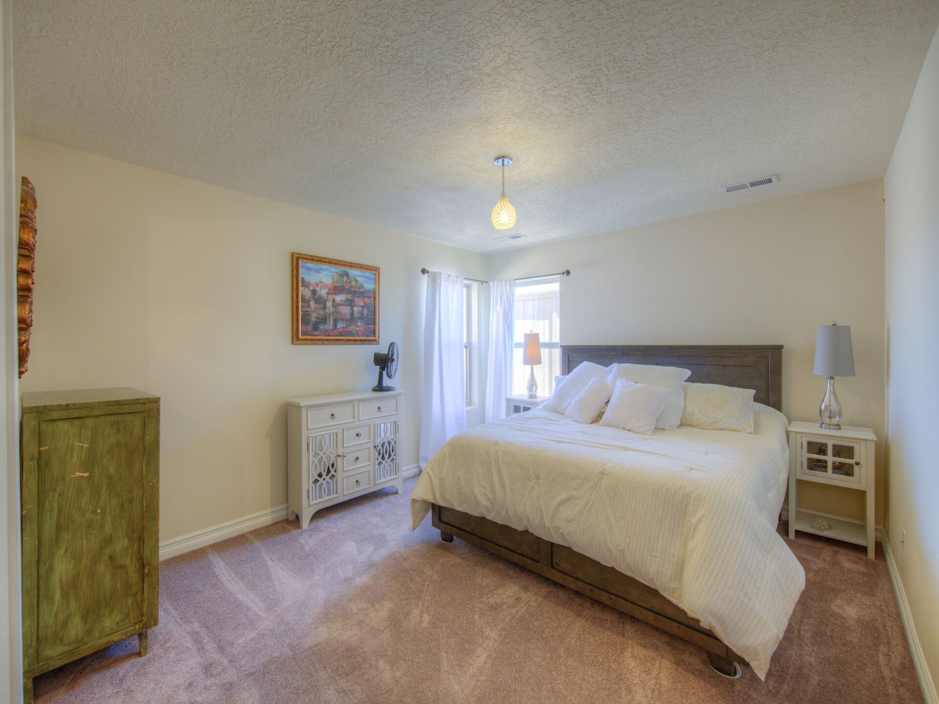 A bedroom with a large bed , dresser , nightstand , and window.