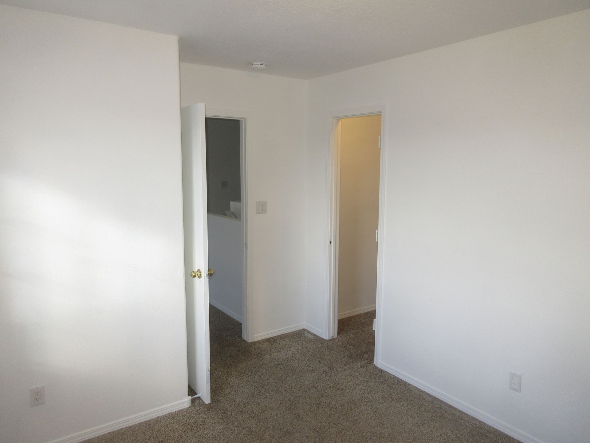 An empty bedroom with a carpeted floor and white walls.