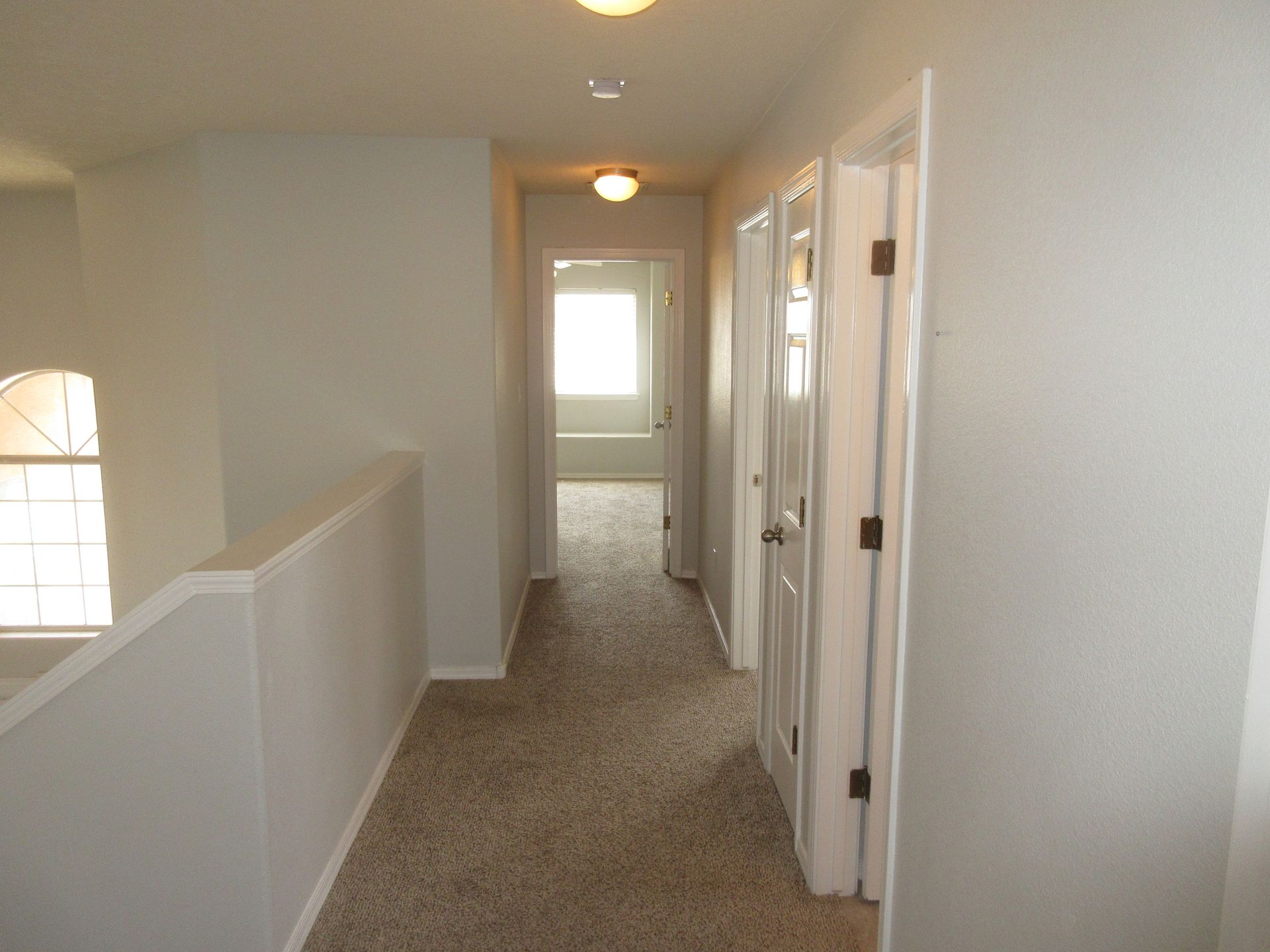 A hallway in a house leading to a bedroom and a bathroom.