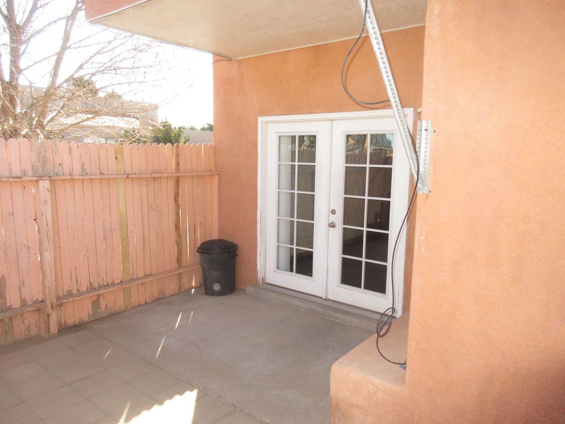 A patio with french doors and a trash can