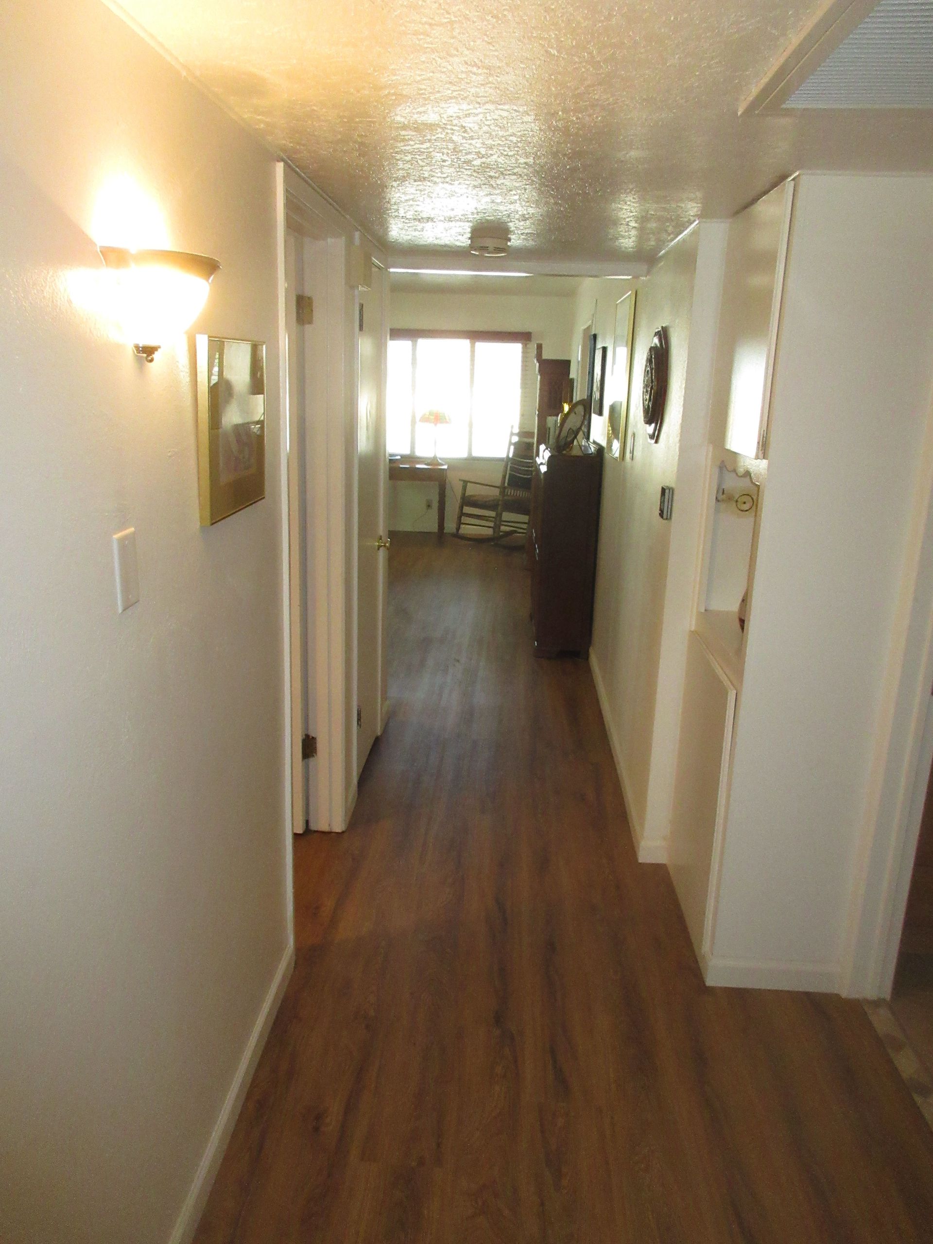 A hallway leading to a living room with hardwood floors