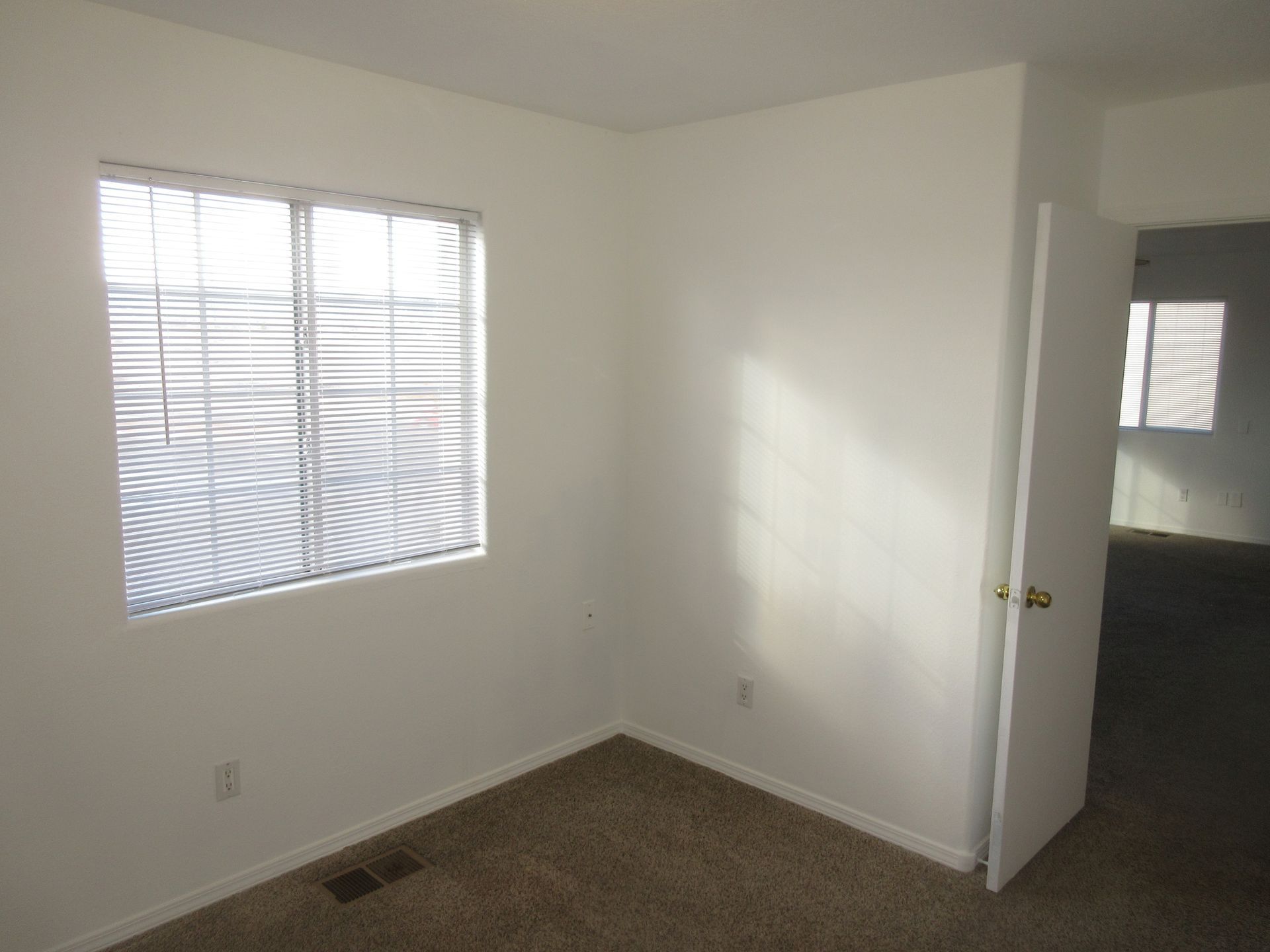 An empty bedroom with a window and blinds