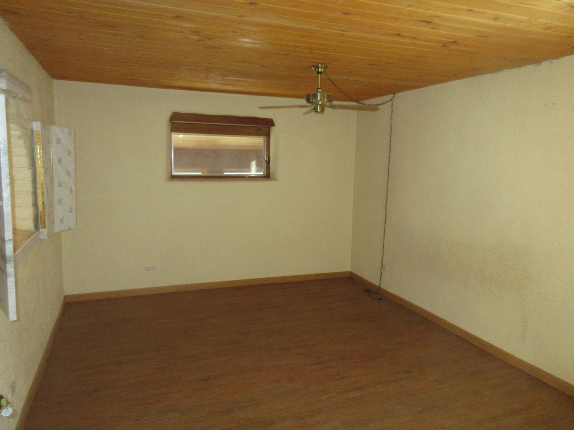An empty room with a ceiling fan and a window.