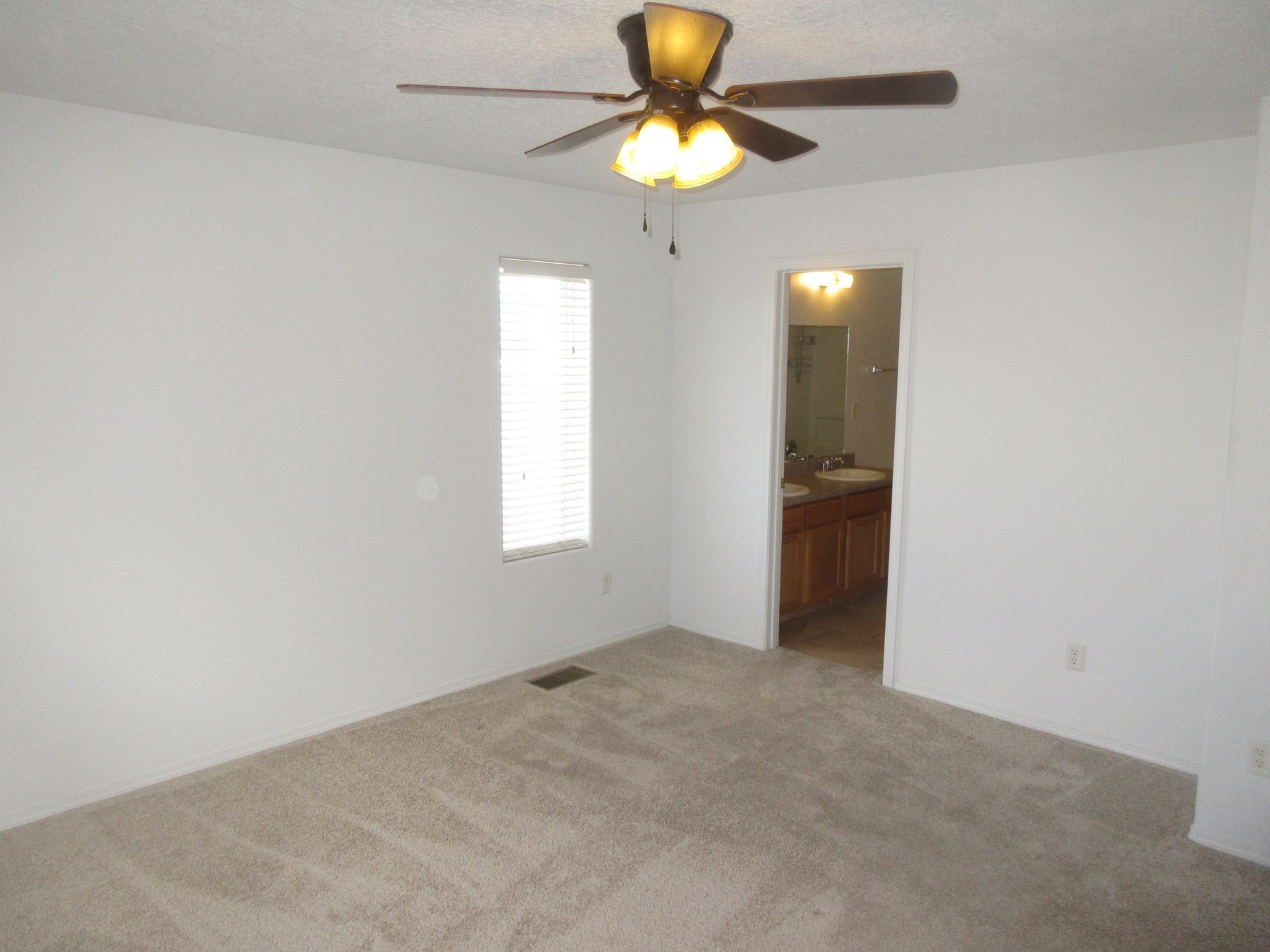 An empty bedroom with a ceiling fan and a window