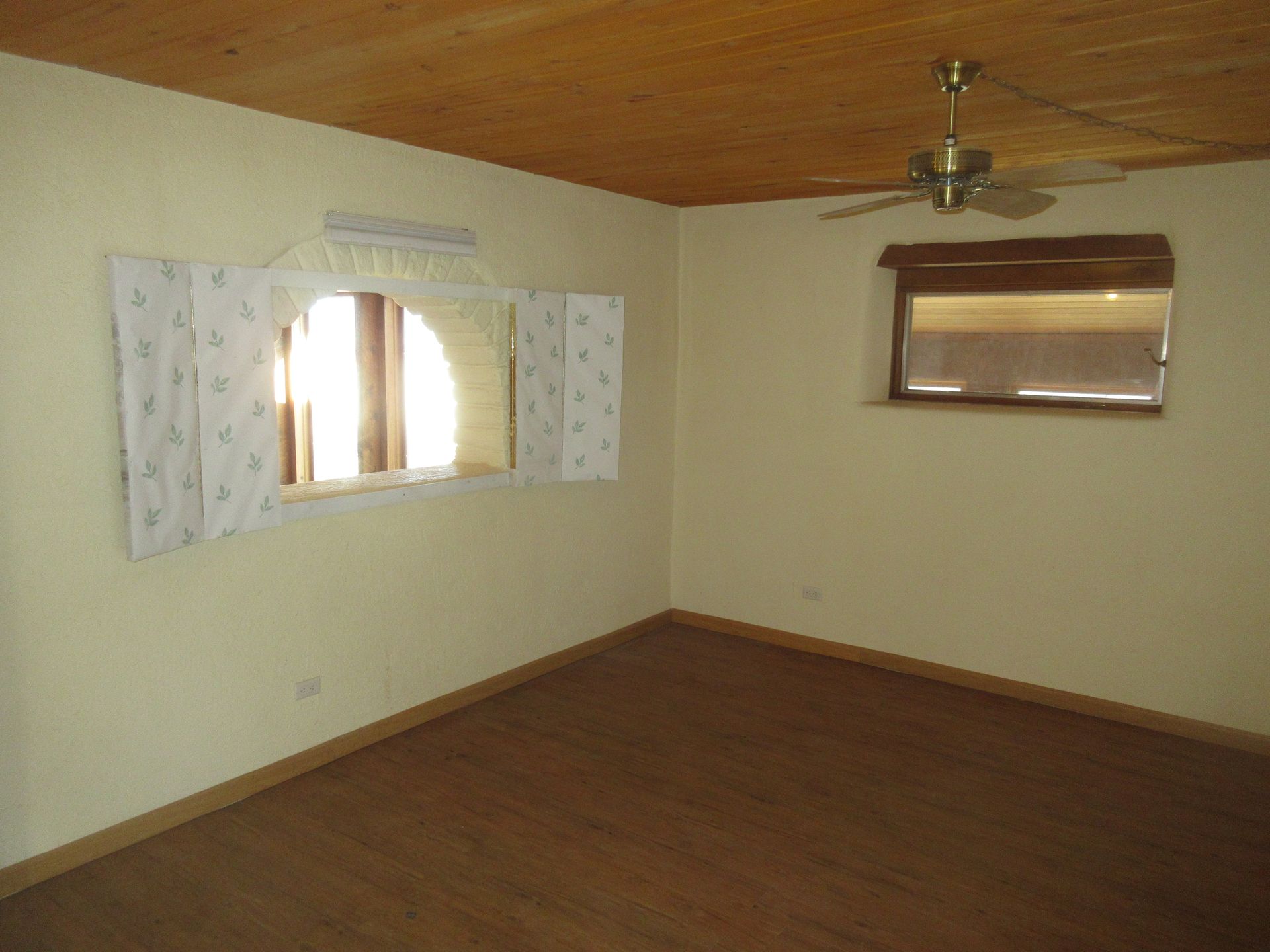 An empty room with a ceiling fan and a window